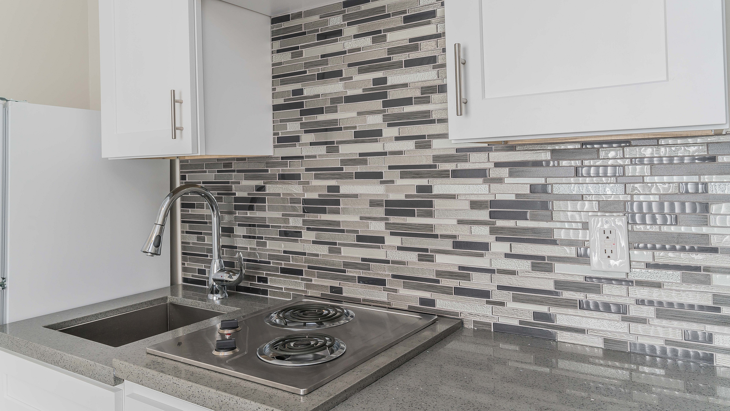 Modern kitchen design with sleek stainless steel appliances, elegant mosaic backsplash, and custom white cabinetry.