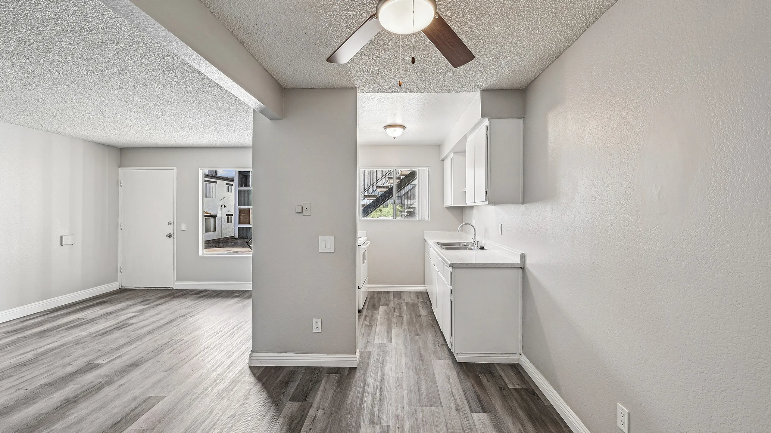 Bright open-plan living area with modern wood flooring and a cozy kitchen, perfect for entertaining.