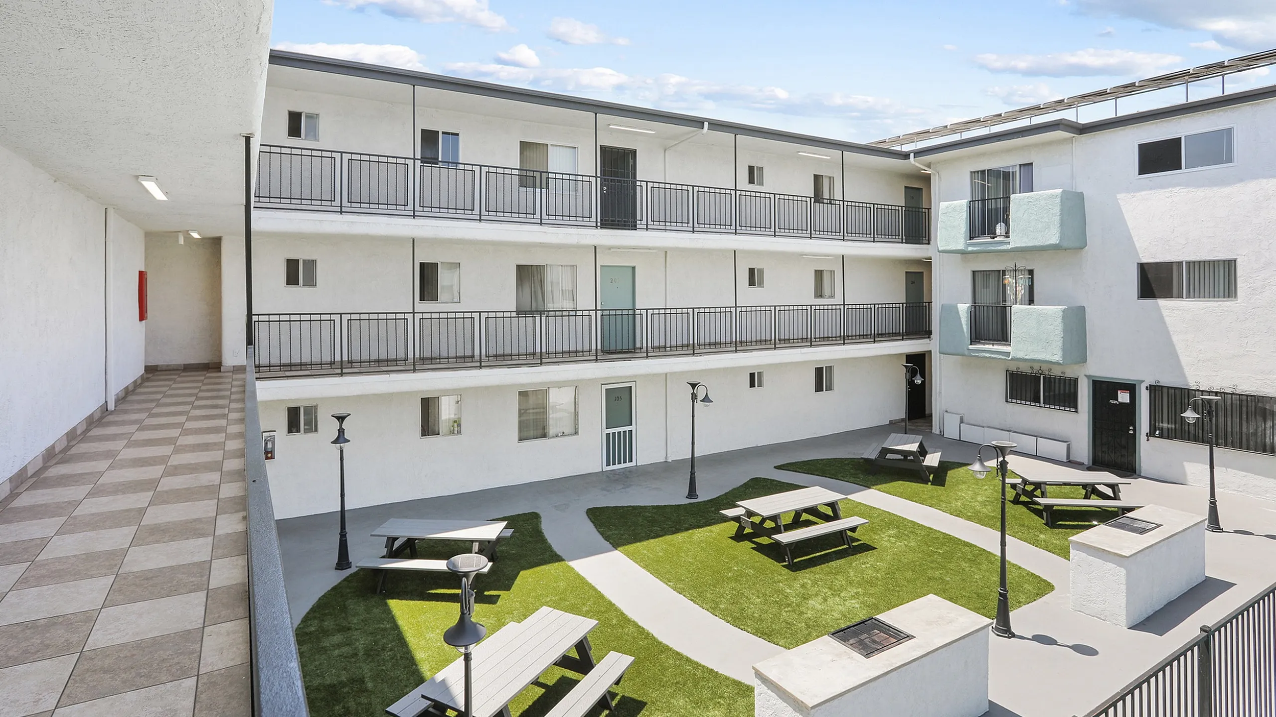 Charming apartment courtyard with spacious balconies and inviting picnic areas, featuring modern architecture and lush greenery.