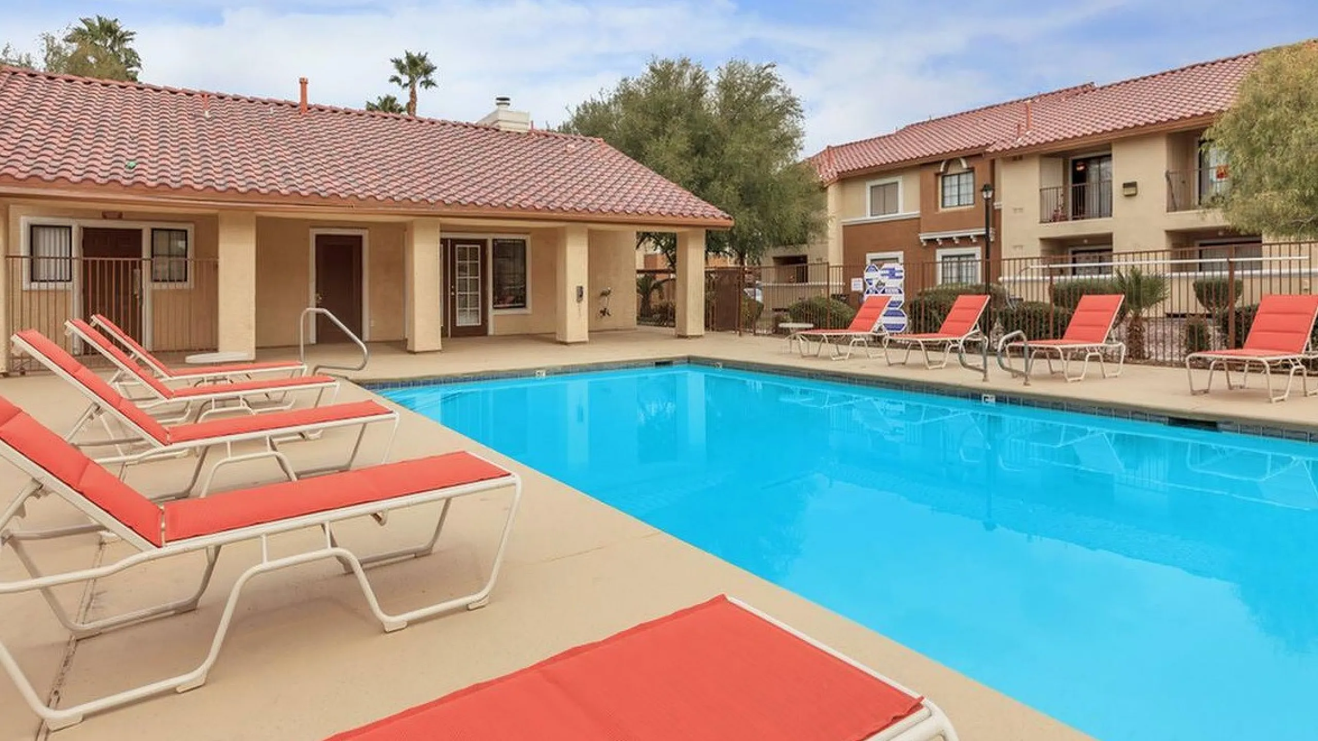Inviting outdoor pool area with vibrant red lounge chairs, perfect for relaxation and enjoyment in this serene residential setting.
