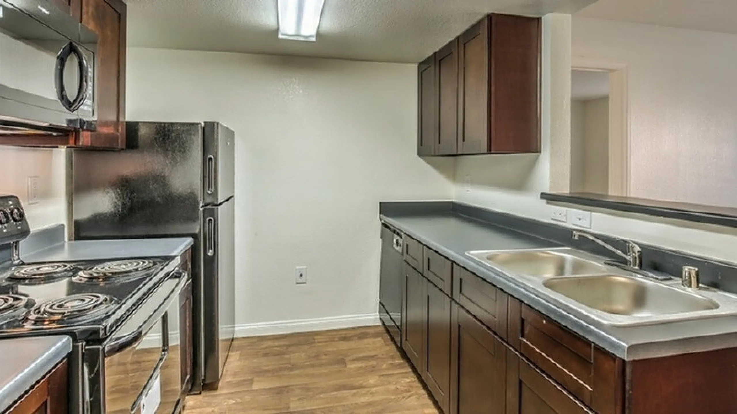 Modern kitchen with sleek dark wood cabinetry, stainless steel appliances, and spacious counters, creating an inviting culinary space.