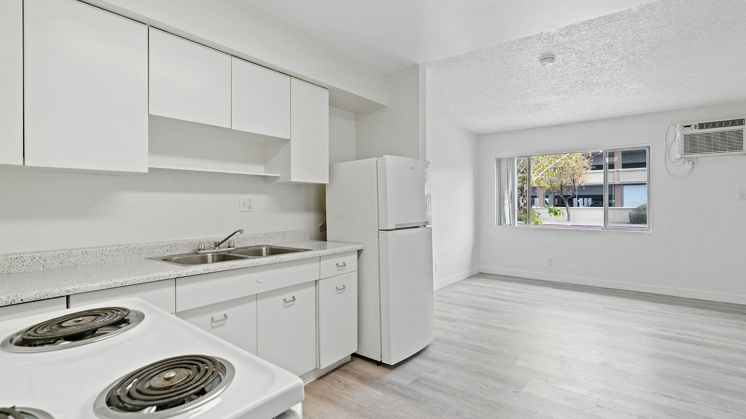 Bright and modern open-plan kitchen with sleek white cabinetry, spacious countertops, and large window bringing in natural light.