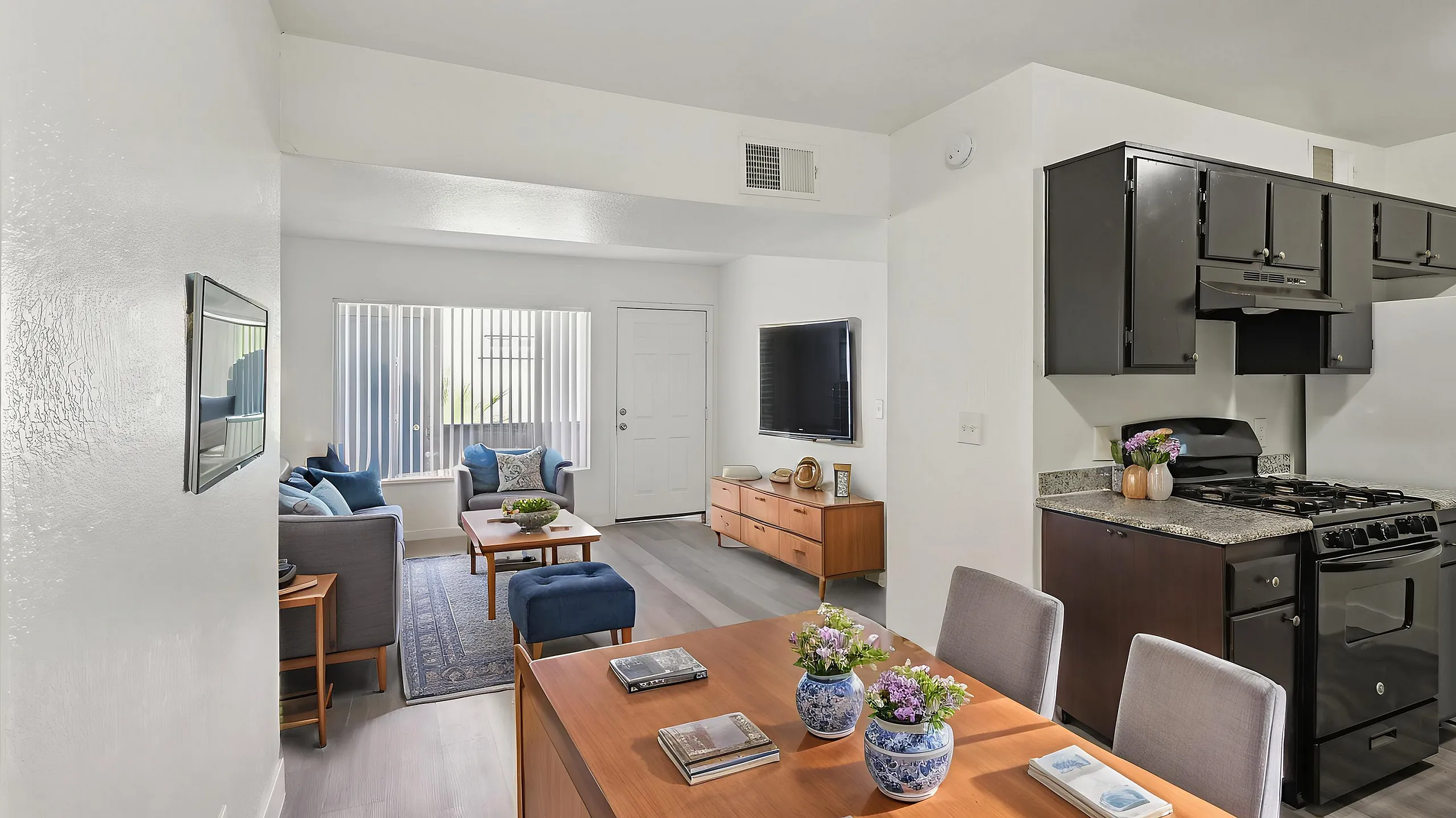 Modern open-concept living space with sleek kitchen, cozy furnished living room, and elegant dining area.