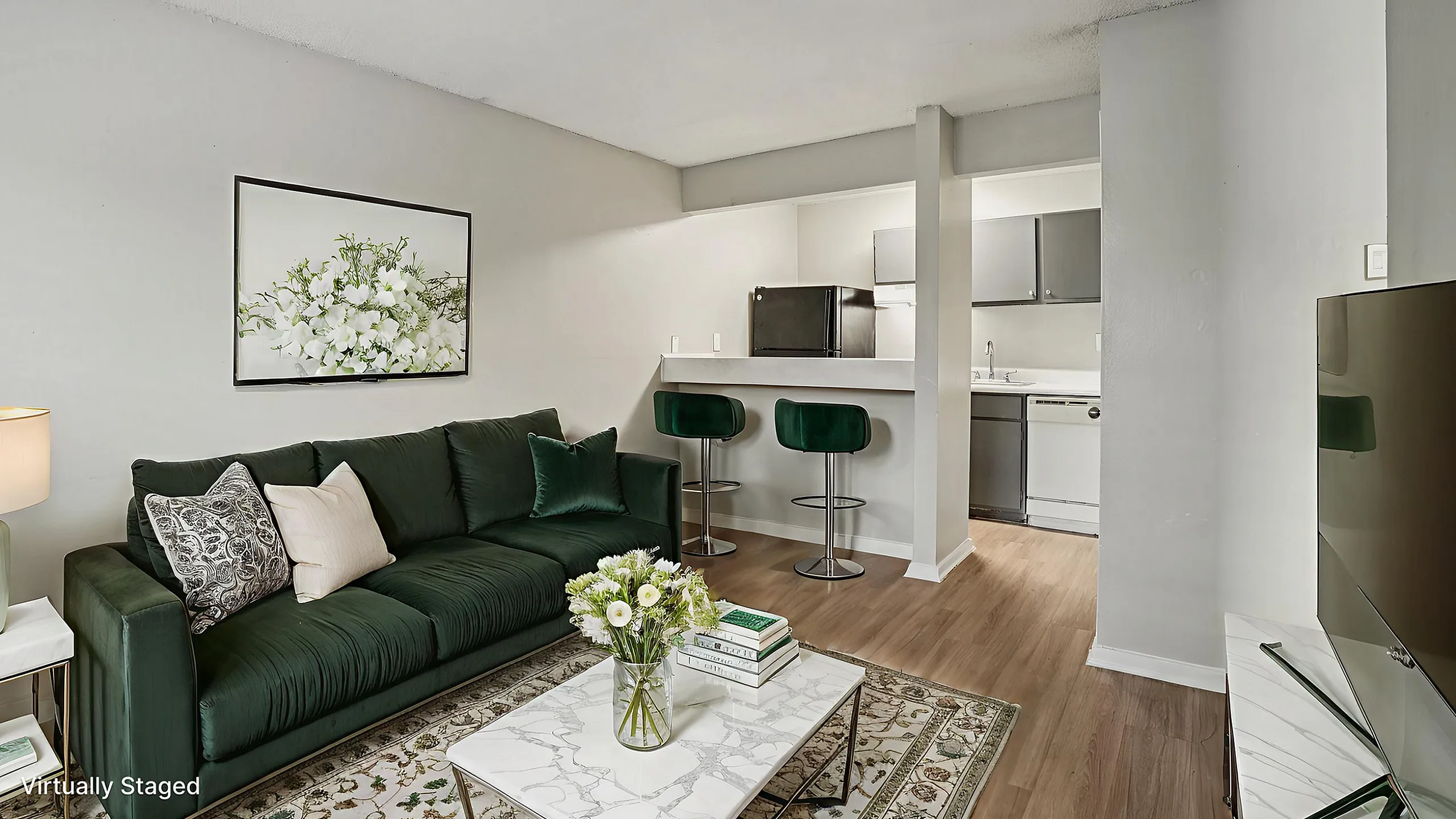 Chic and modern living room with elegant dark green sofa, sleek white marble table, and cozy open kitchen with bar seating.