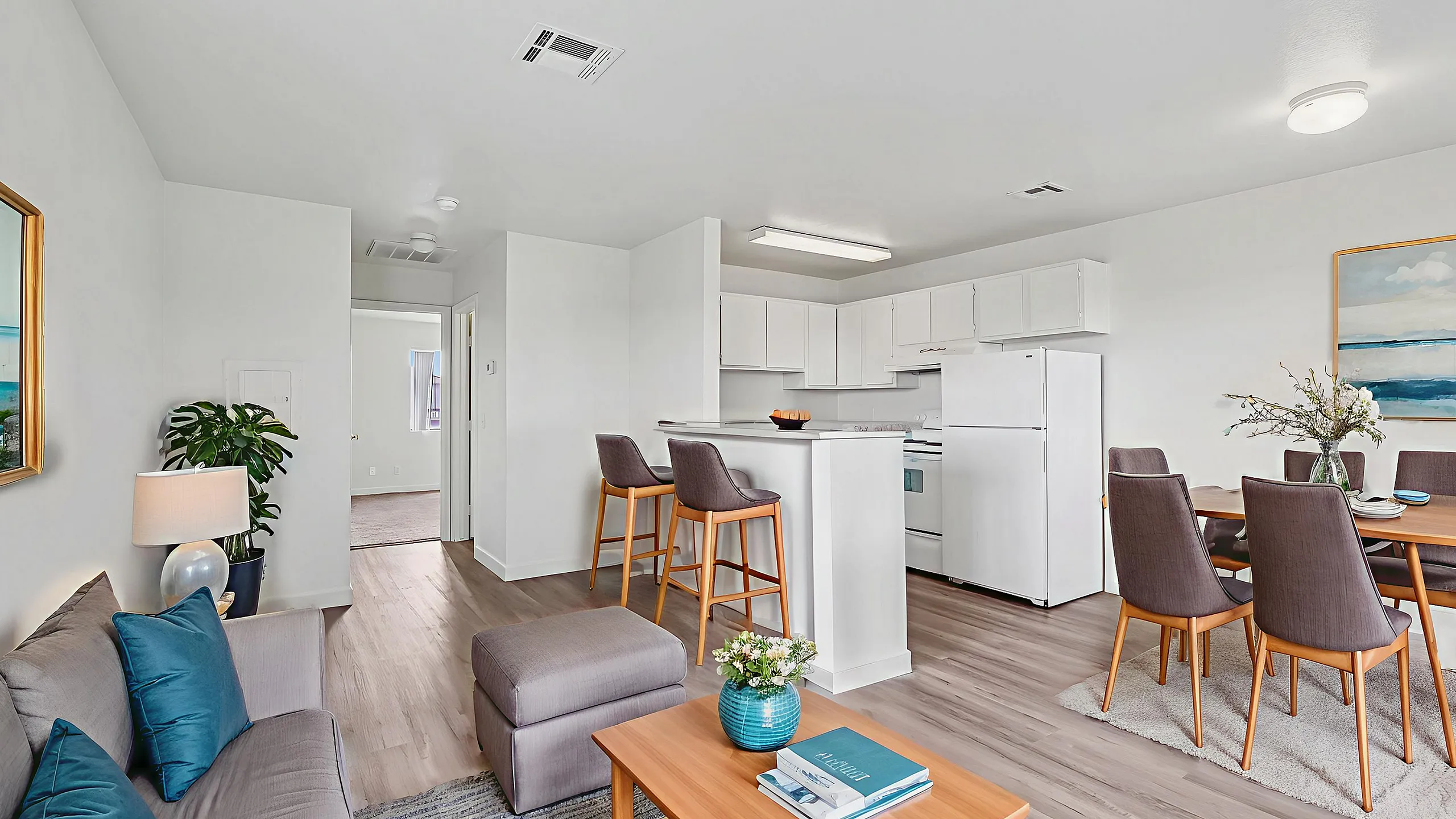 Bright and inviting virtually staged living room and kitchen area with modern furnishings, bar seating, and elegant dining space.