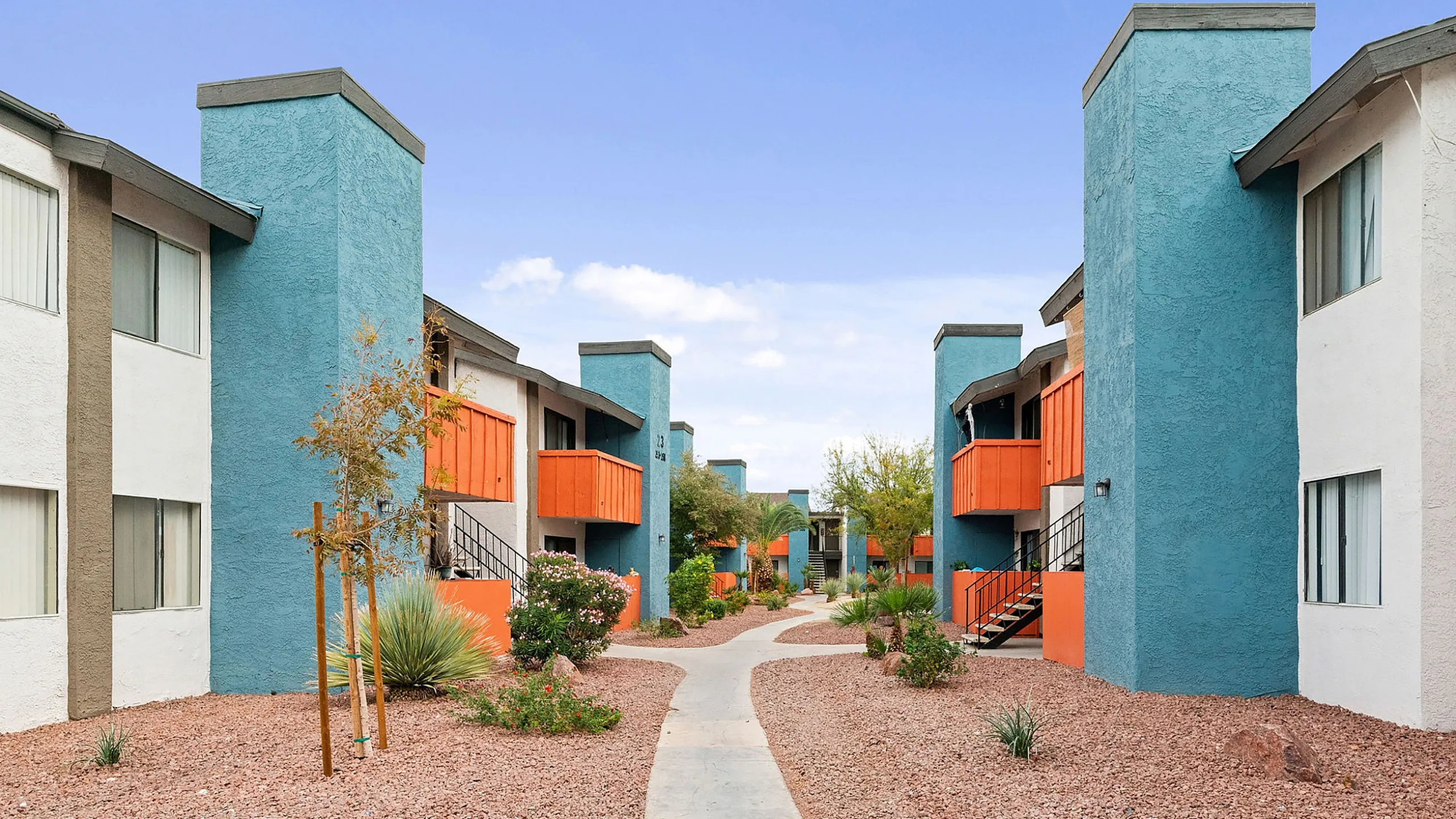 Vibrant apartment complex with colorful facades and well-maintained desert landscaping, offering a welcoming and modern living environment.