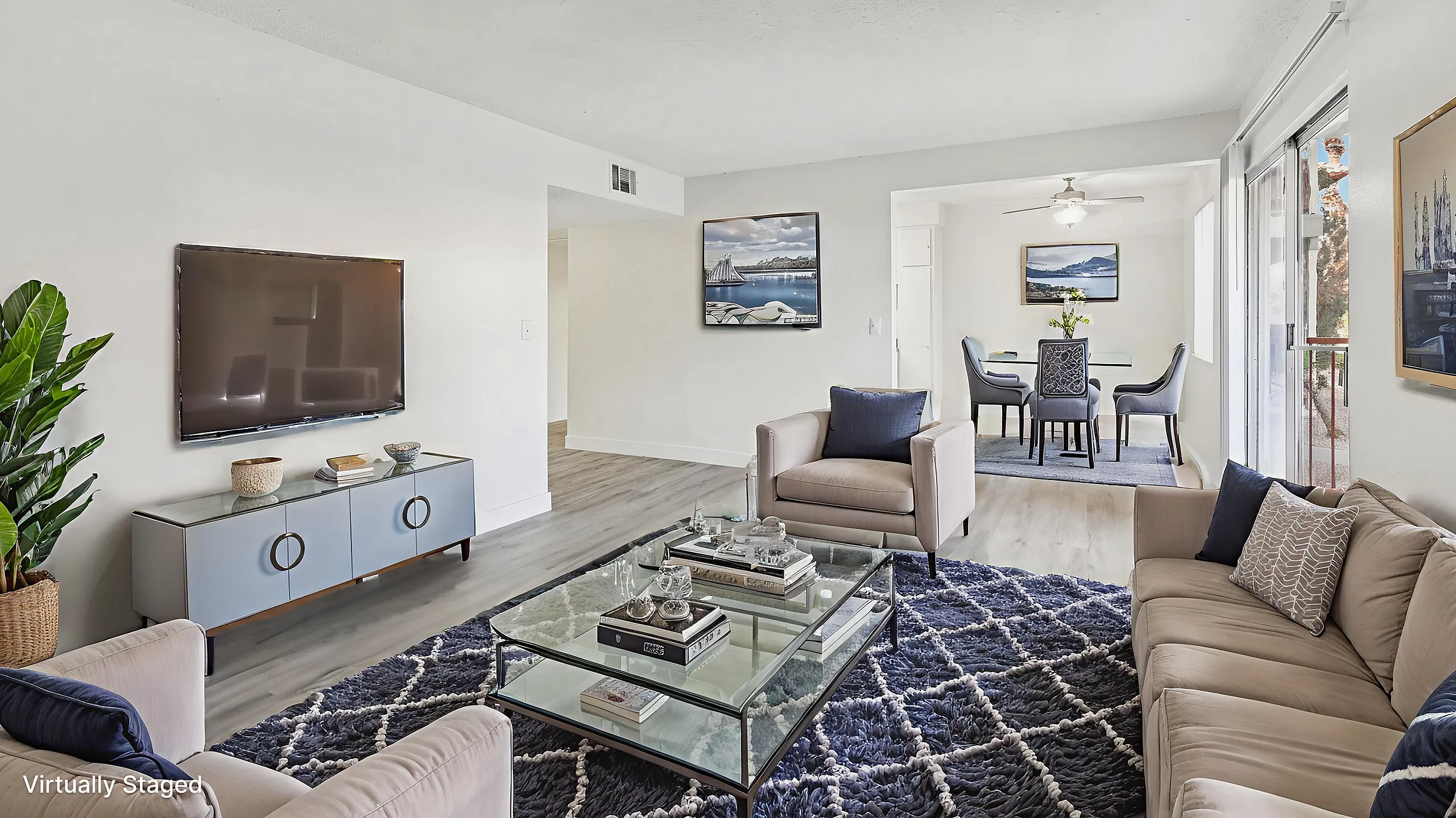 Elegantly staged living room featuring contemporary furniture, a stylish glass coffee table, and a modern TV setup, seamlessly flowing into a chic dining area with natural light.