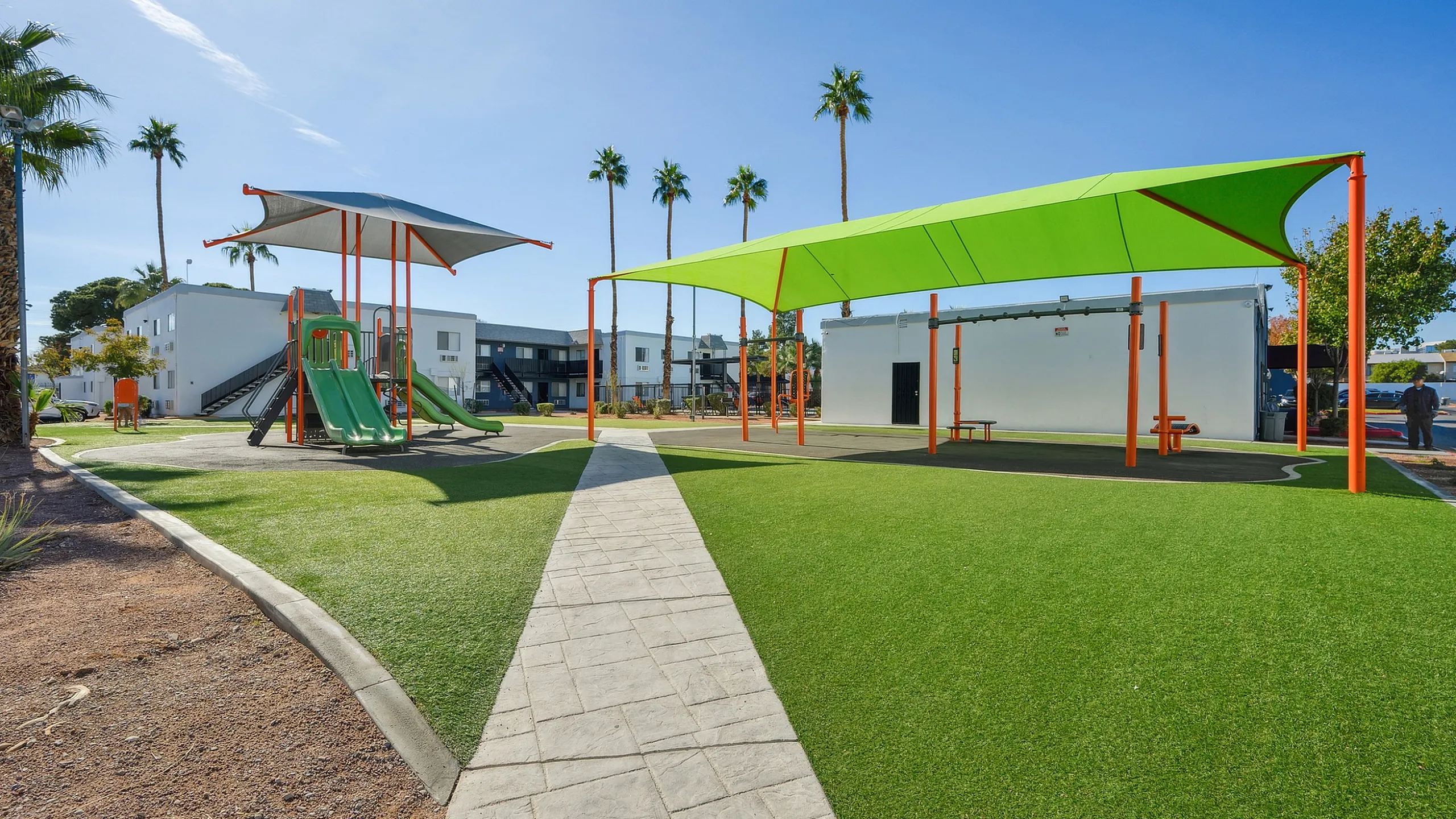 Vibrant community playground with modern slides and shaded seating, set against a backdrop of palm trees and stylish apartments.