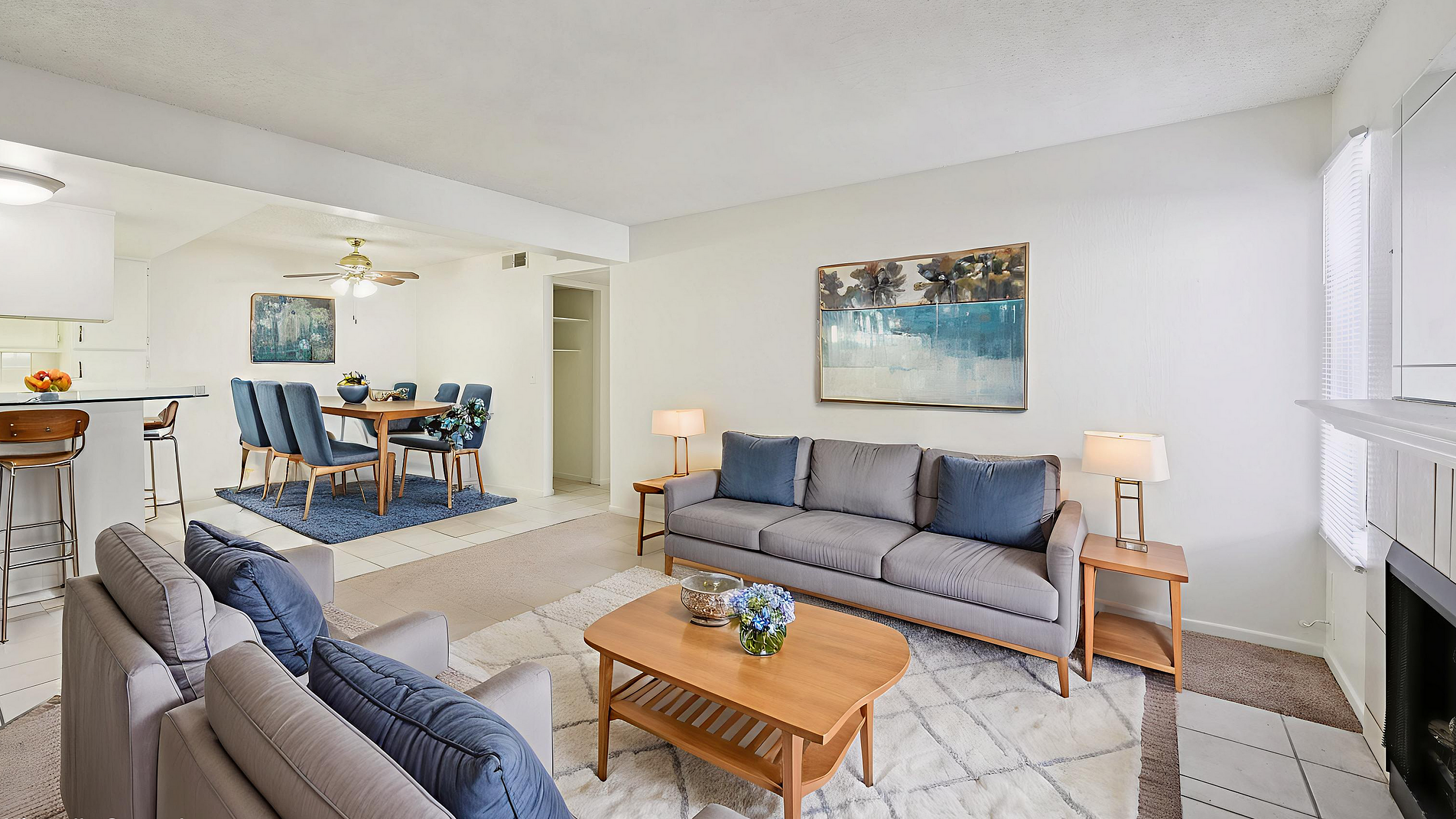 Elegantly staged open-concept living area featuring a cozy seating arrangement, modern dining space, and a stylish kitchen with a breakfast bar.