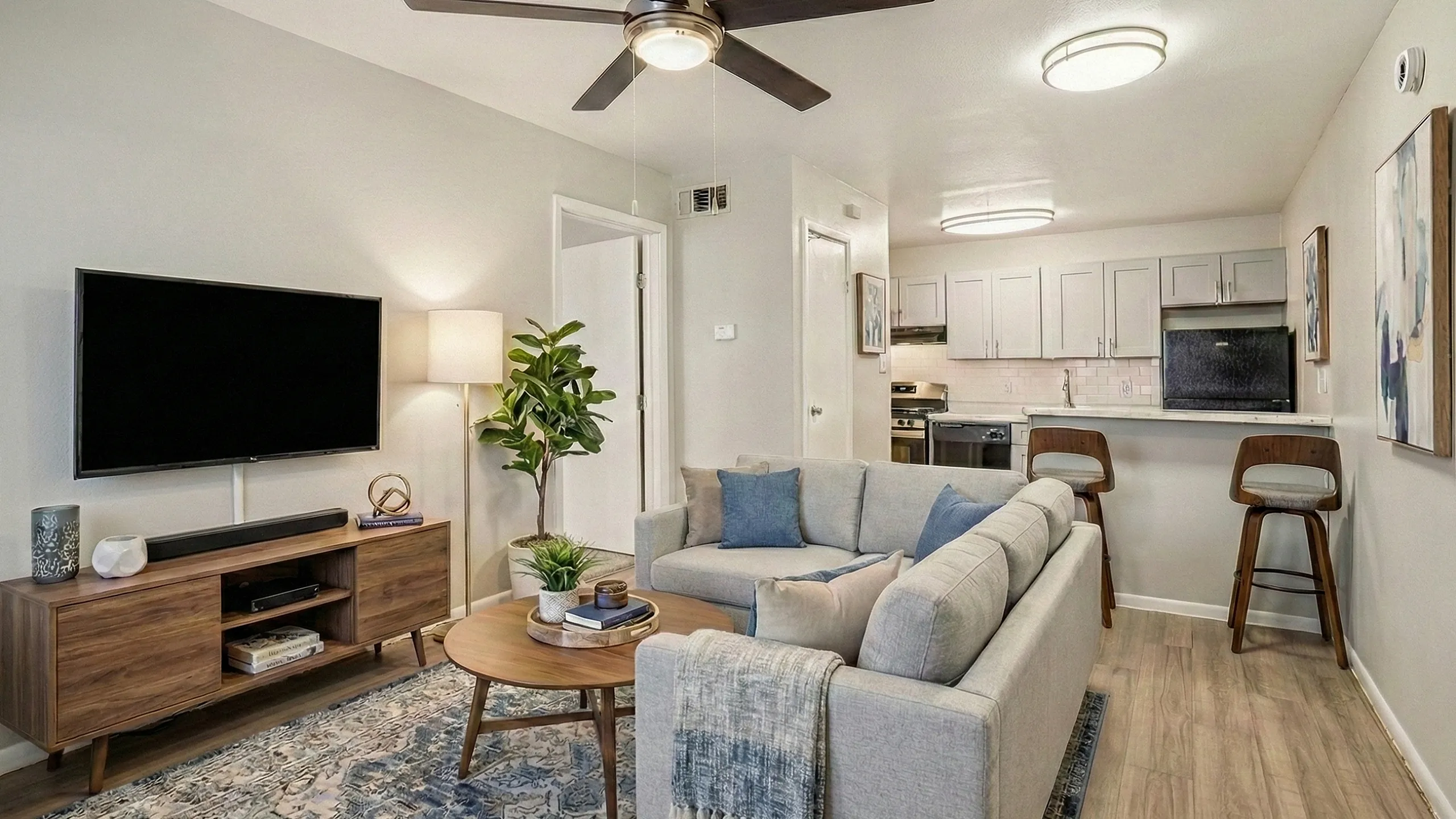 Chic open-plan living area with a cozy gray sofa, modern decor, and stylish kitchen with breakfast bar seating.