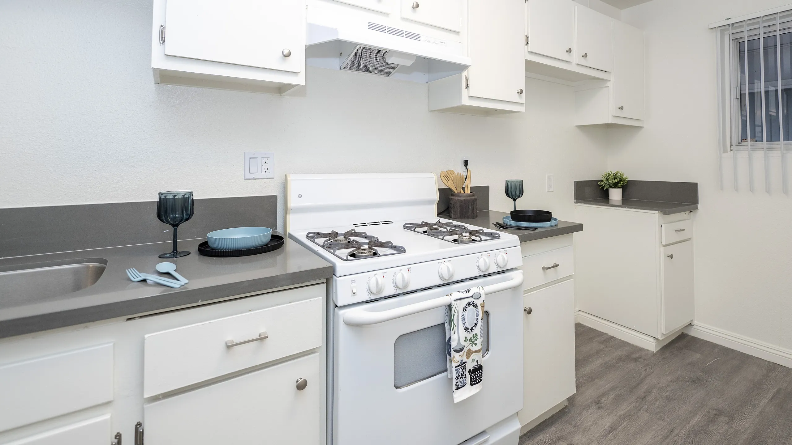 Bright, modern kitchen featuring sleek white cabinetry, elegant gray countertops, and a cozy breakfast nook atmosphere.