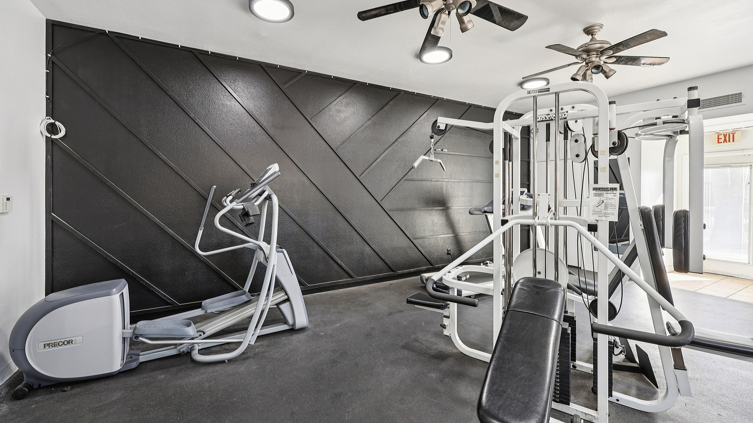 Modern gym area with sleek exercise equipment and stylish black accent wall.