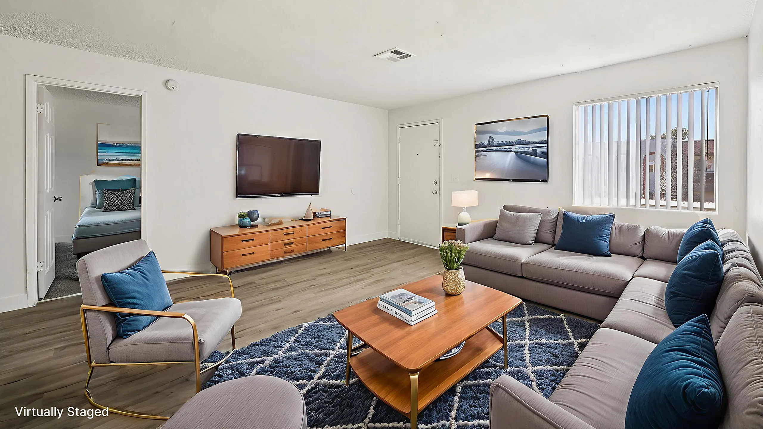 Bright and inviting living room with modern decor, large sectional sofa, chic coffee table, and wall-mounted TV. Features an abundance of natural light and stylish laminate flooring.