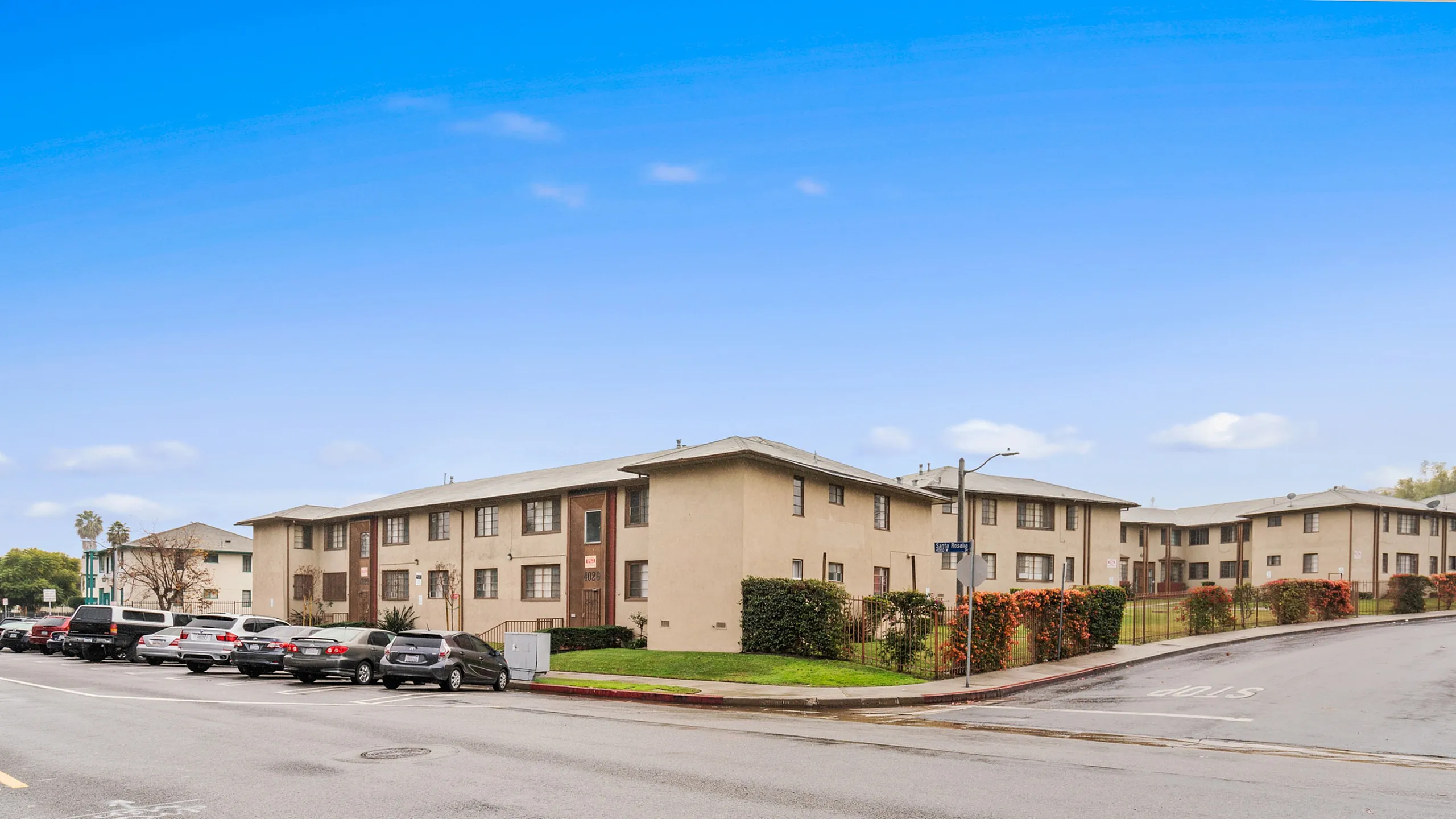 Inviting apartment complex with well-maintained landscaping and convenient street parking under a clear blue sky.