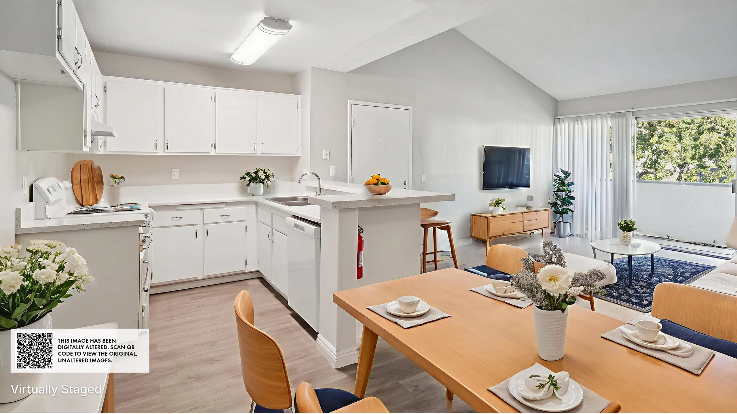 Bright open-plan living area with sleek white kitchen, cozy dining space, and inviting lounge opening to large windows with lush views.