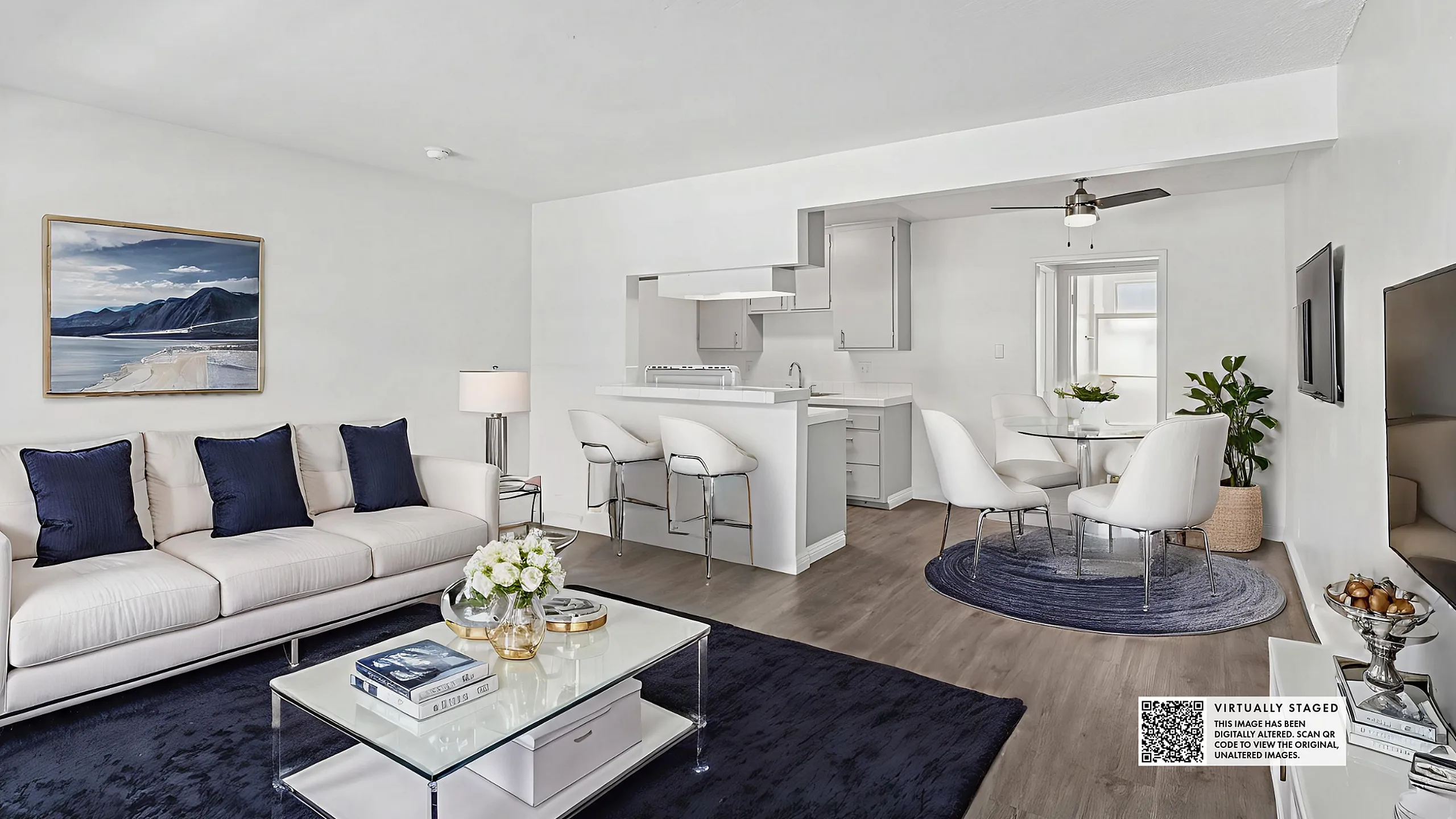 Elegant, open-concept living area with a chic white sofa, sleek kitchen, and stylish dining space. Modern decor and soft color palette create a welcoming ambiance.