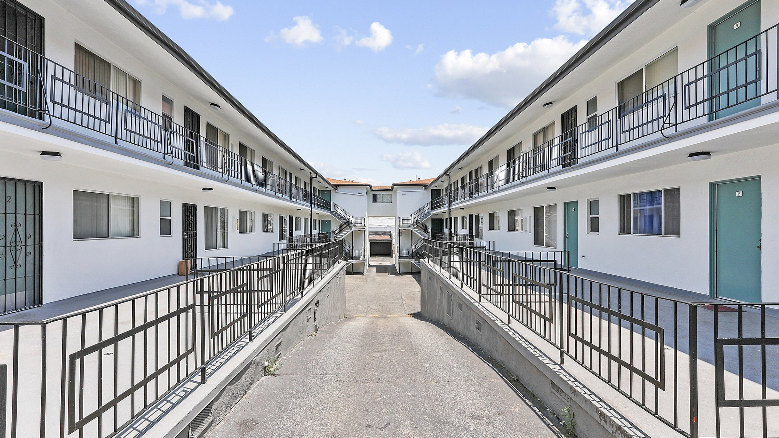 Contemporary apartment complex with a clean, symmetric design and sunny courtyard, offering modern living spaces.