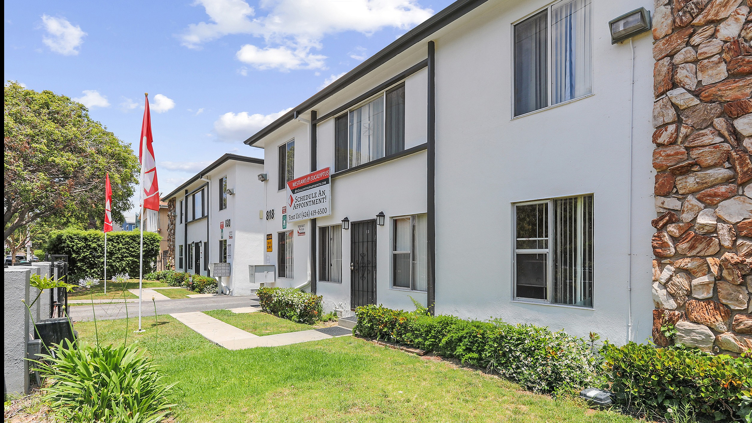 Charming apartment exterior with modern design, lush landscaping, and inviting pathway.