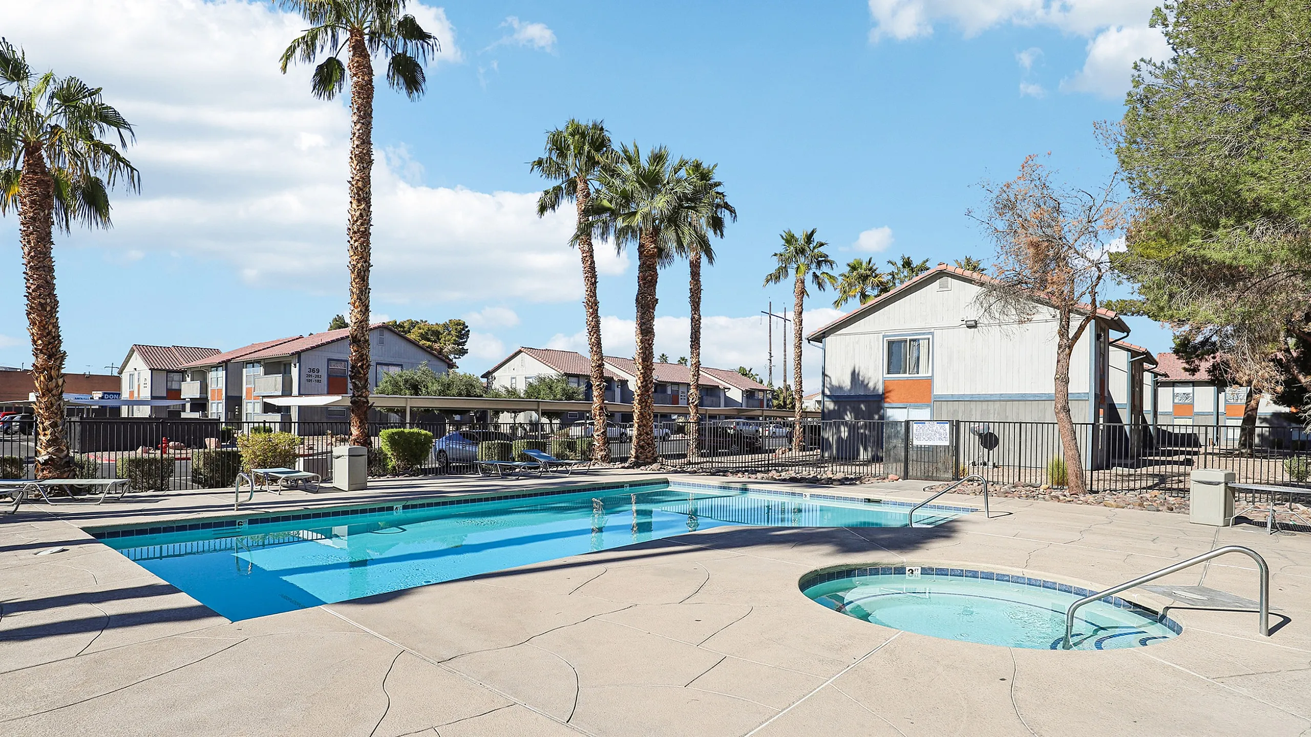 Inviting outdoor pool area with sun loungers, surrounded by palm trees and scenic views, offering a perfect relaxation spot.