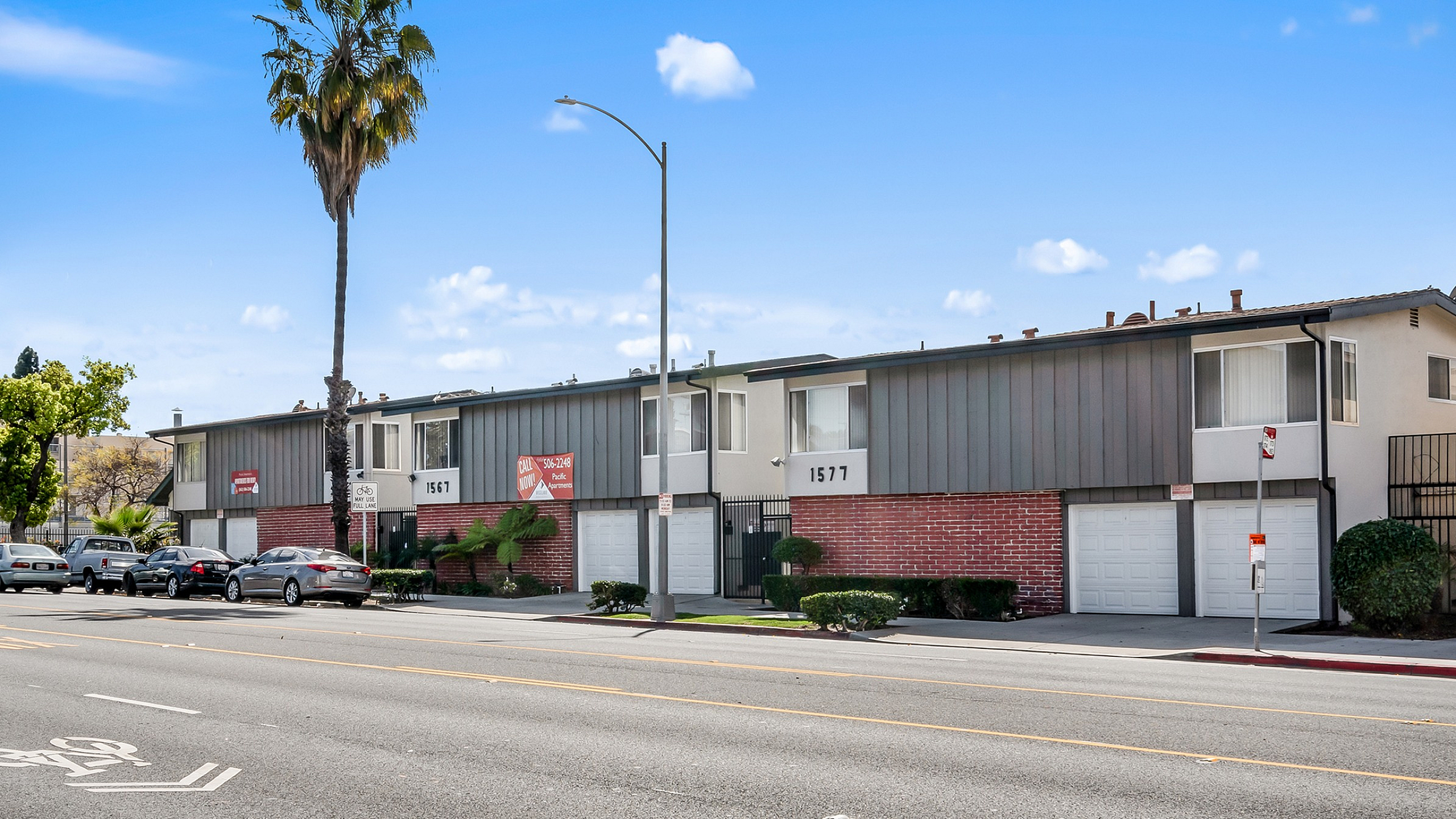 Charming urban apartment complex with red brick facade and manicured greenery, offering convenient location and modern living.