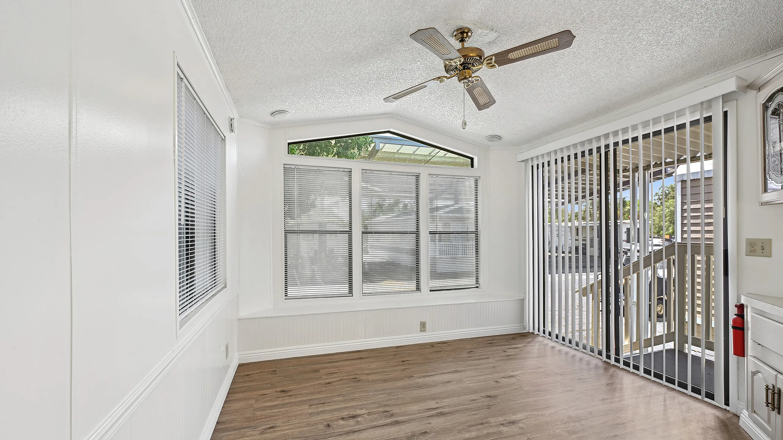 Bright, inviting room with large windows, elegant wood flooring, and modern ceiling fan for a chic living space.