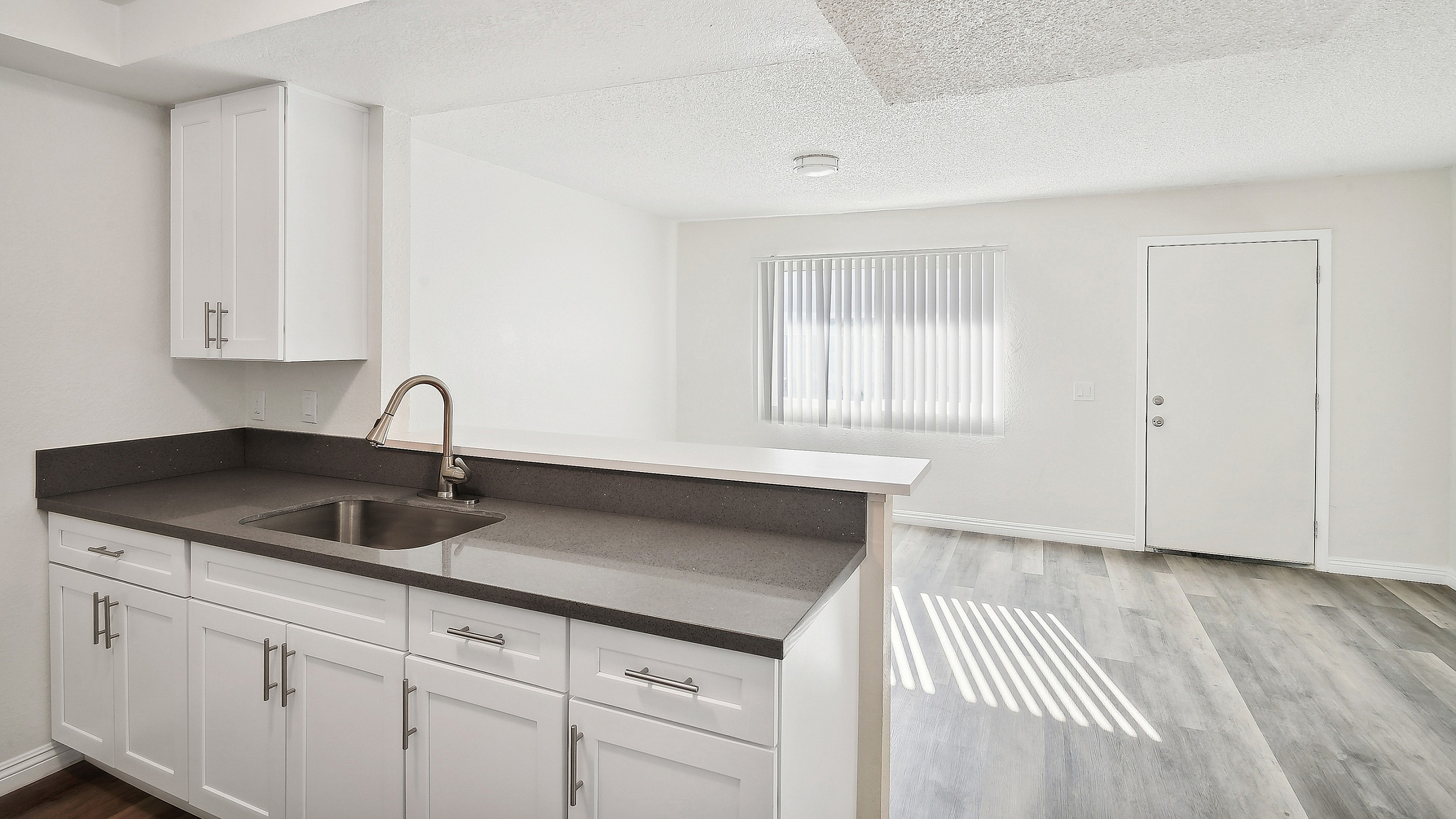 Bright and modern open-plan kitchen with sleek white cabinetry and an inviting living area bathed in natural light.