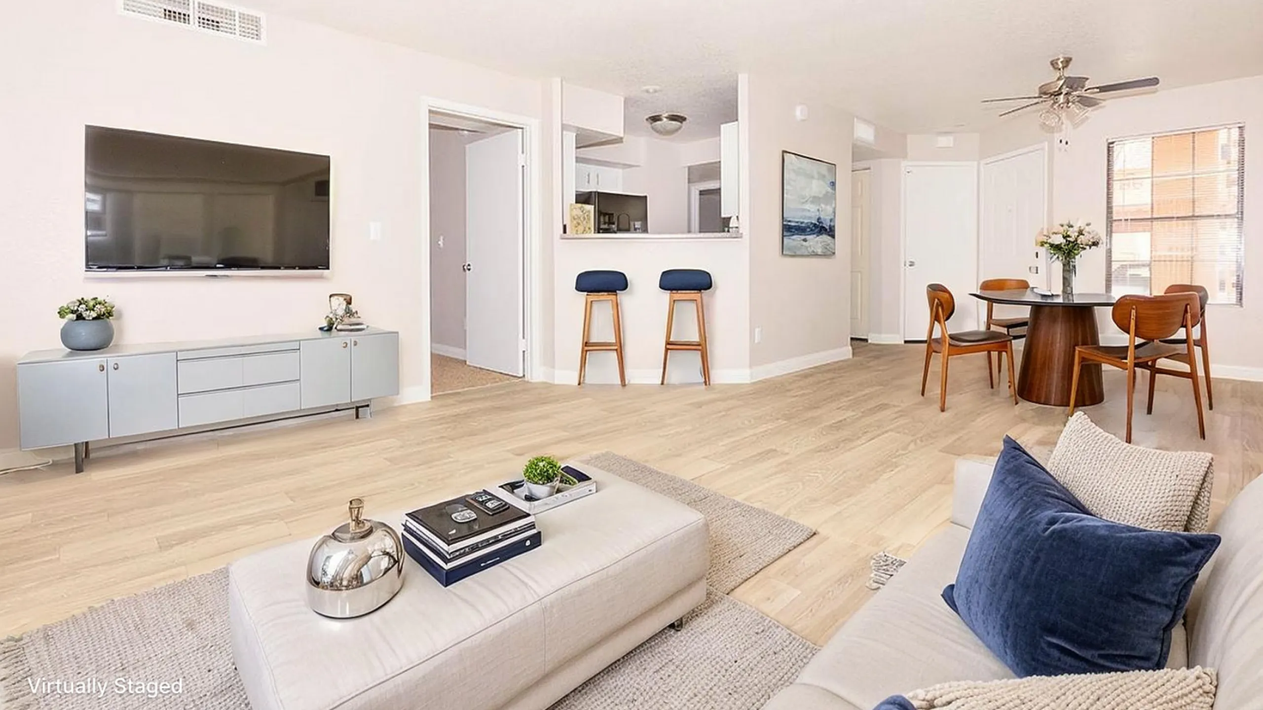 Bright and modern living space featuring open floor concept, sleek kitchen bar with stools, and elegant dining area with large windows.