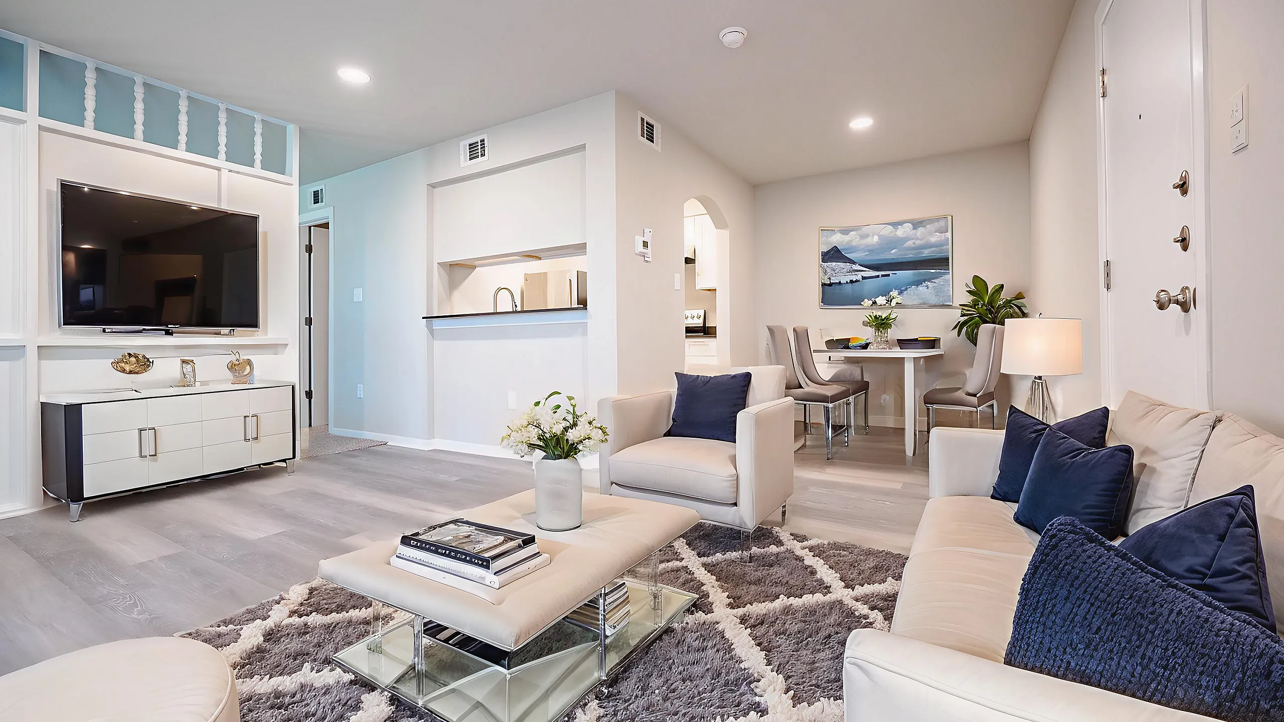 Elegantly staged living room with modern furniture, spacious layout, and stylish decor, featuring a flat-screen TV and a cozy dining area.