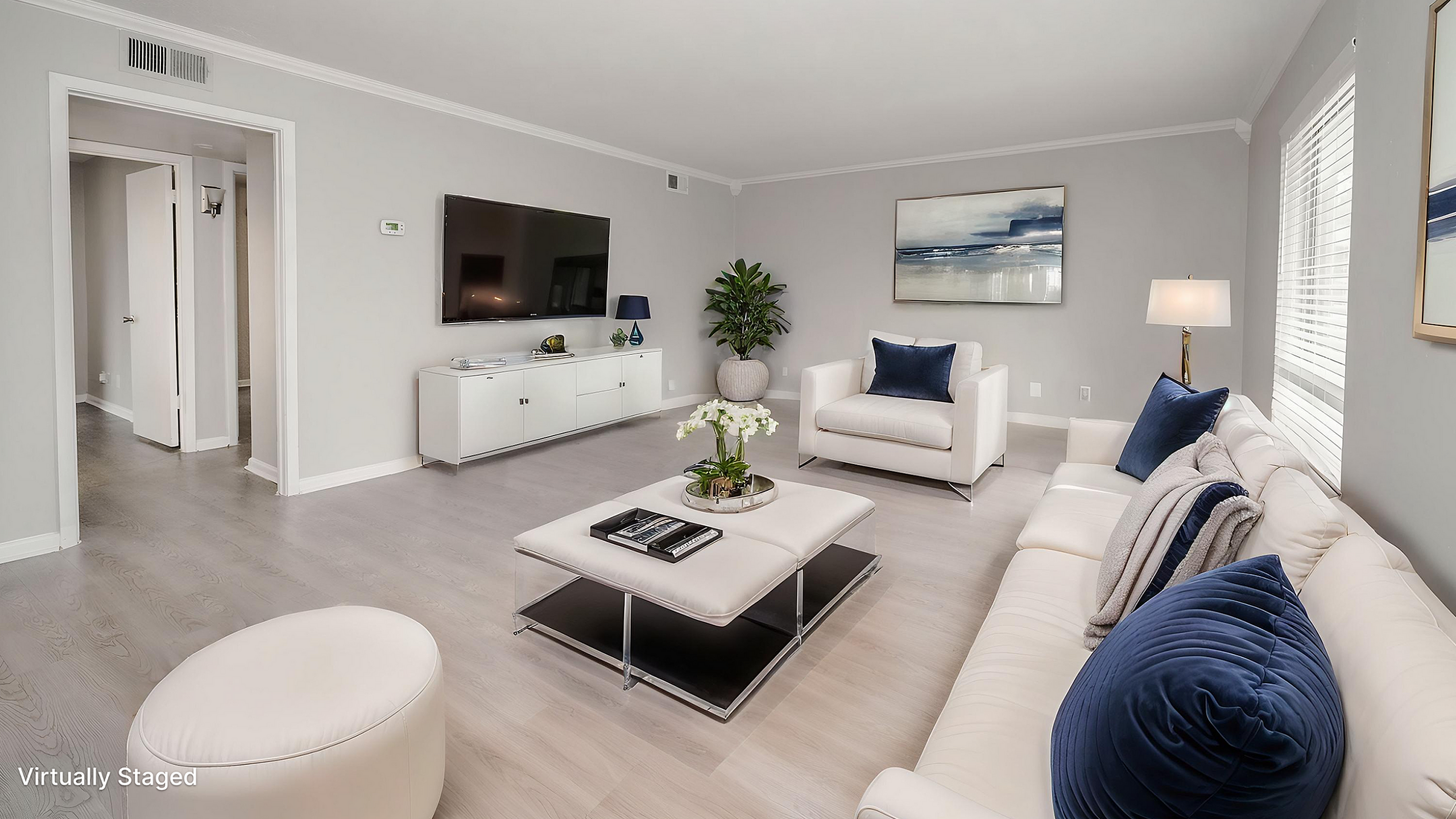 Chic and inviting living room with modern decor, plush white sofas, and sleek decor, all bathed in natural light.