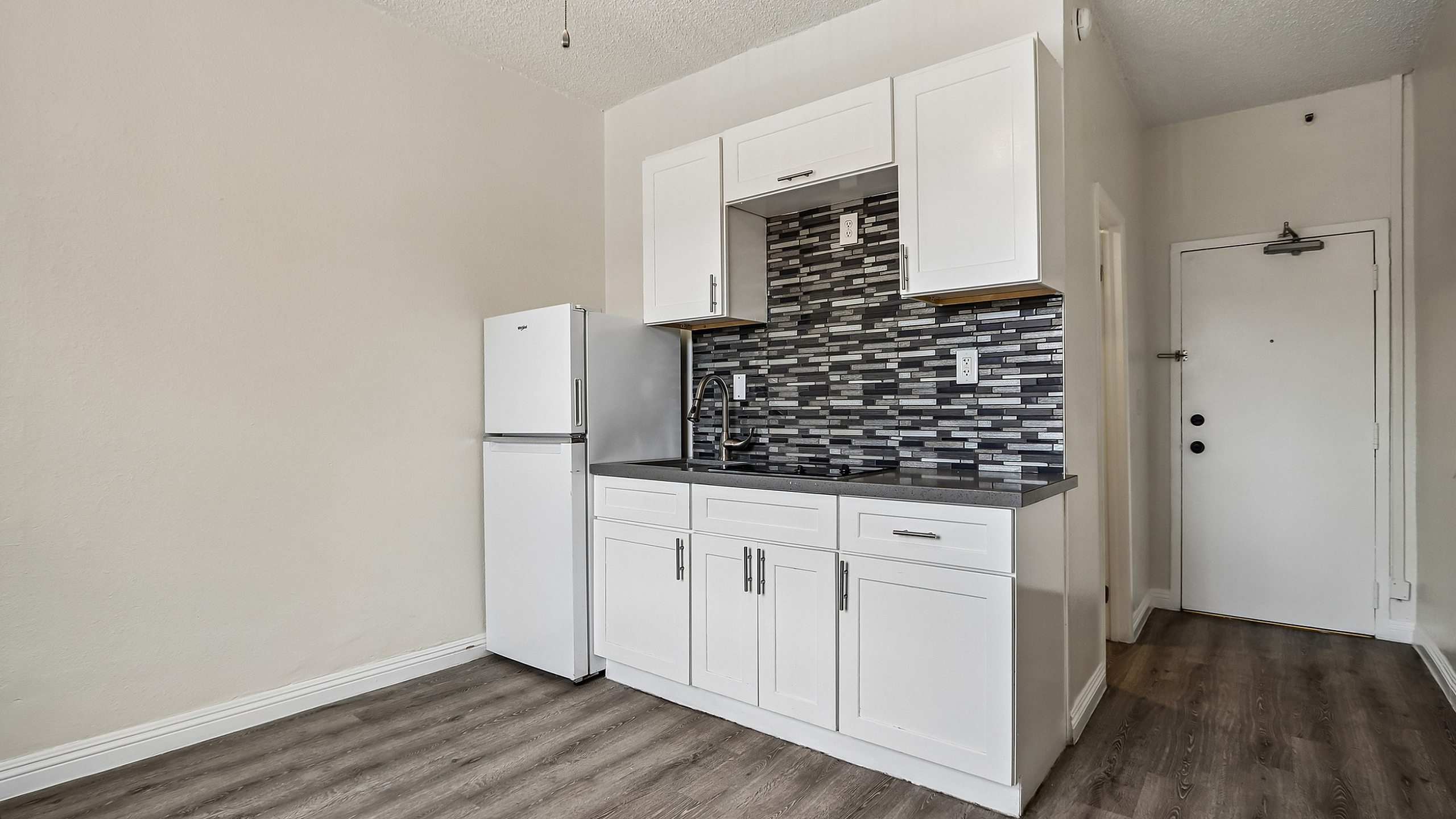 Contemporary kitchen with sleek white cabinets, stylish subway tile backsplash, and modern flooring, perfect for a chic apartment living space.