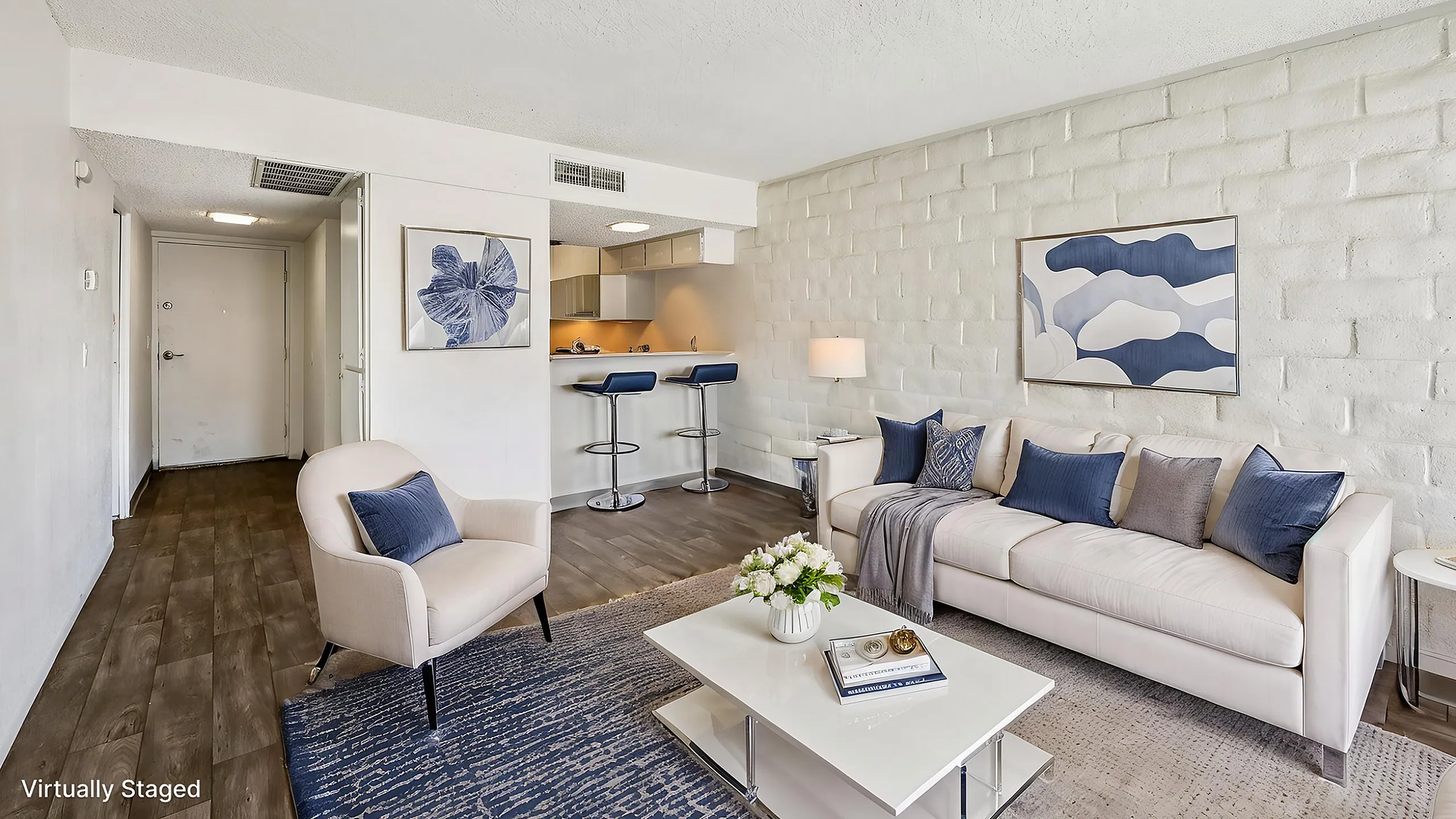 Chic open-concept living space with modern decor, cozy seating, and a stylish breakfast bar with two stools.