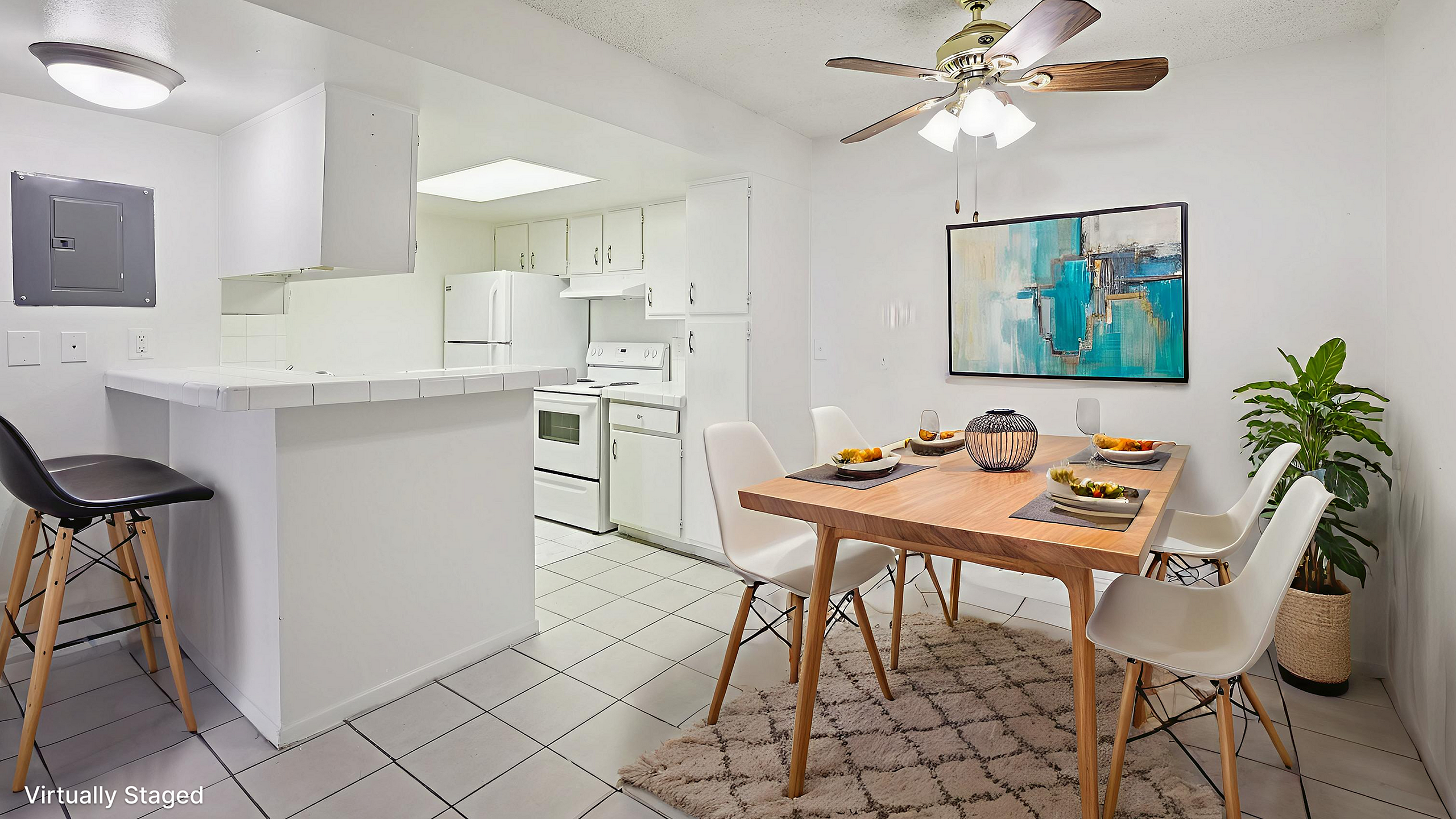 Bright and inviting kitchen and dining area with modern decor and natural lighting, featuring white cabinetry, a cozy dining set, and stylish artwork.