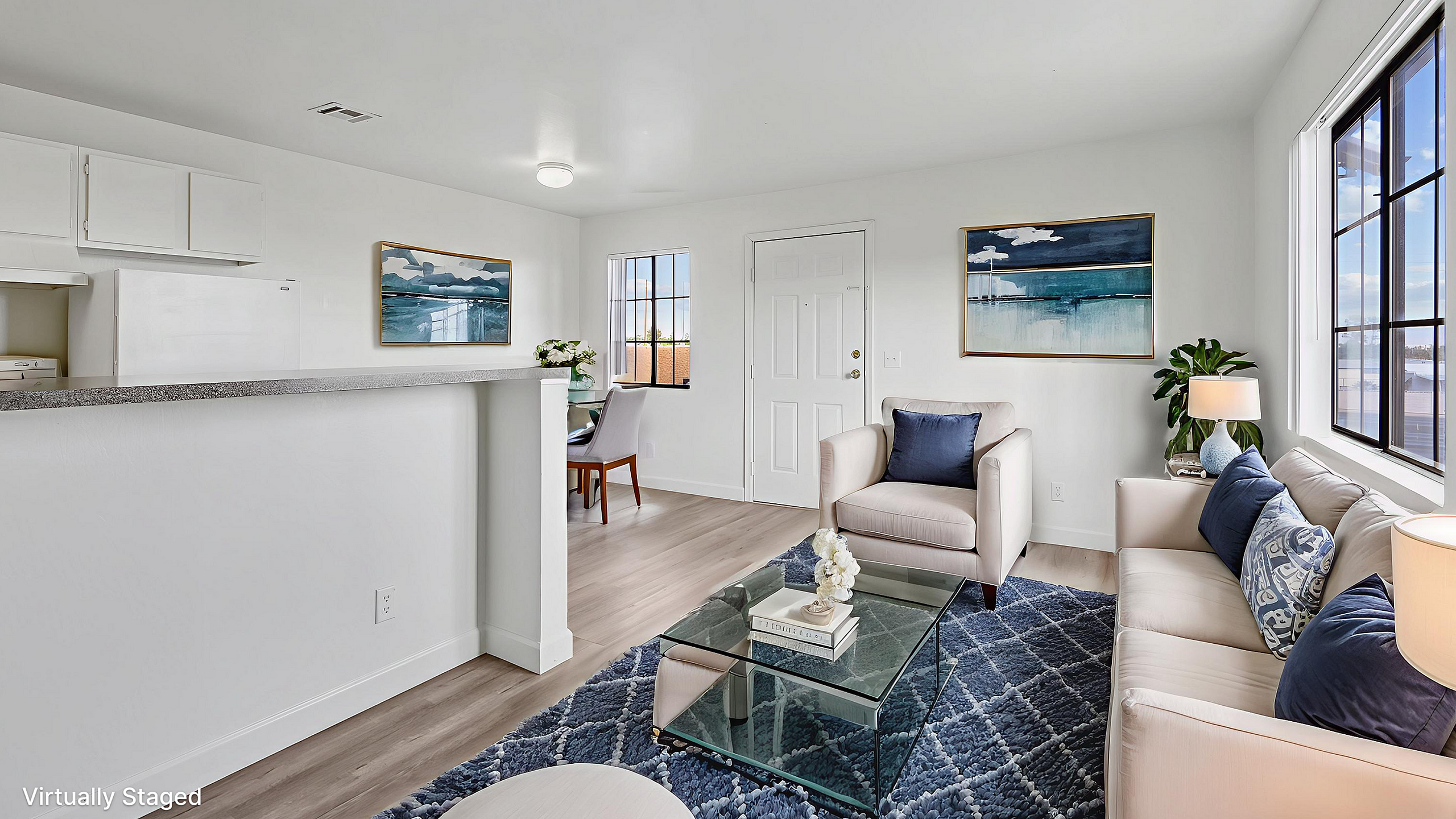Brightly lit living room featuring stylish modern decor, plush seating, and an inviting open-plan layout with a sleek kitchen area.