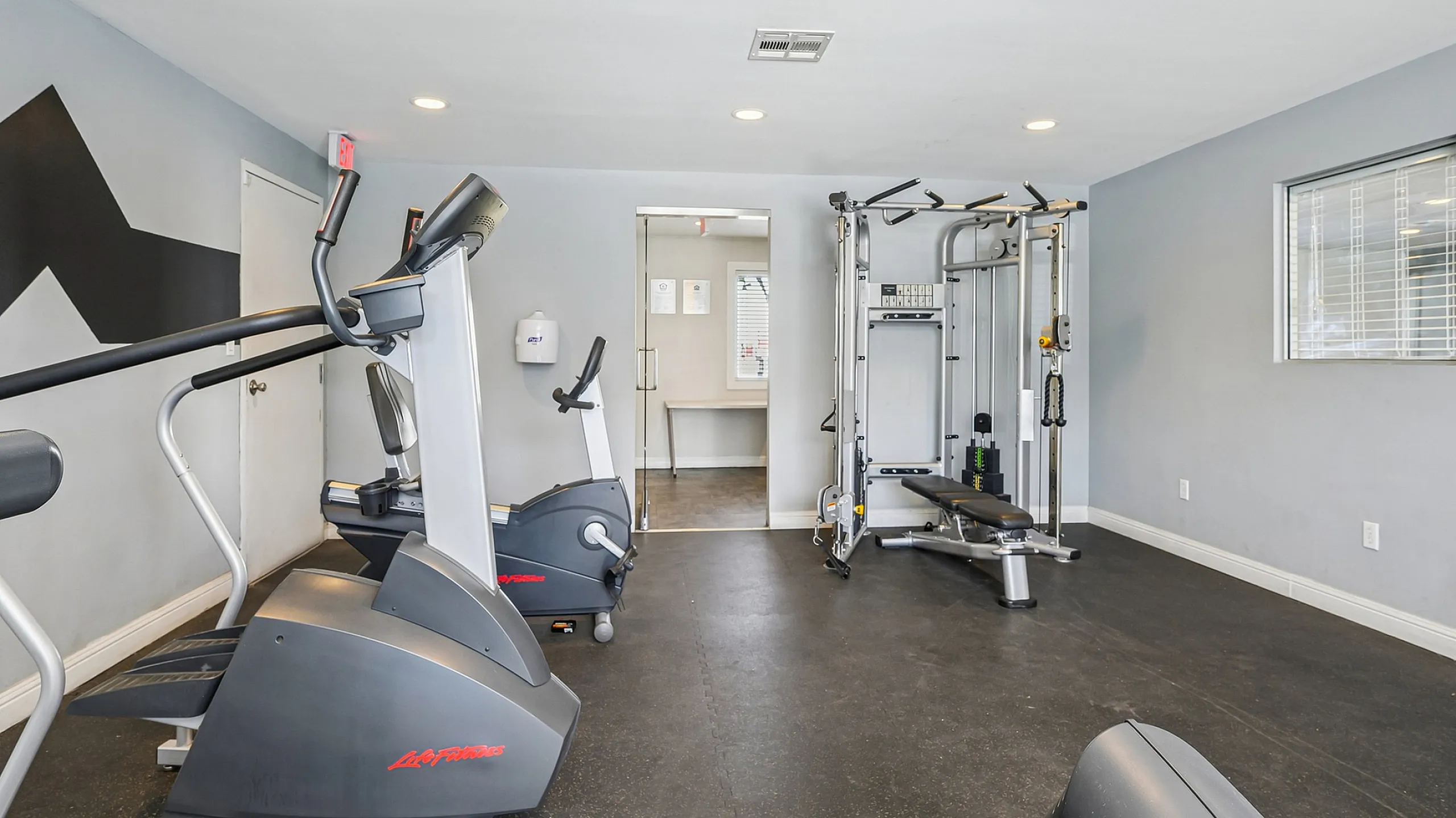 Modern fitness center with state-of-the-art exercise equipment, including treadmills and a multifunctional weight machine.