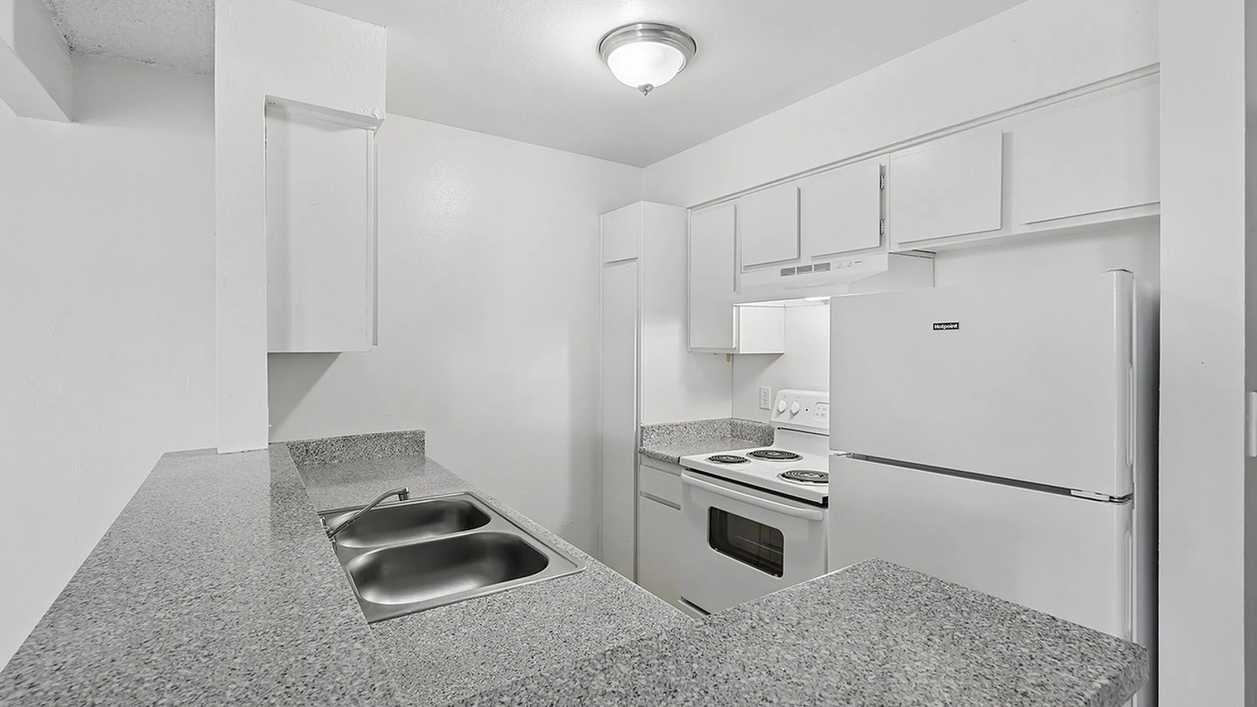 Modern kitchen with sleek granite countertops, white cabinetry, and stainless steel sink offering a clean, contemporary feel.