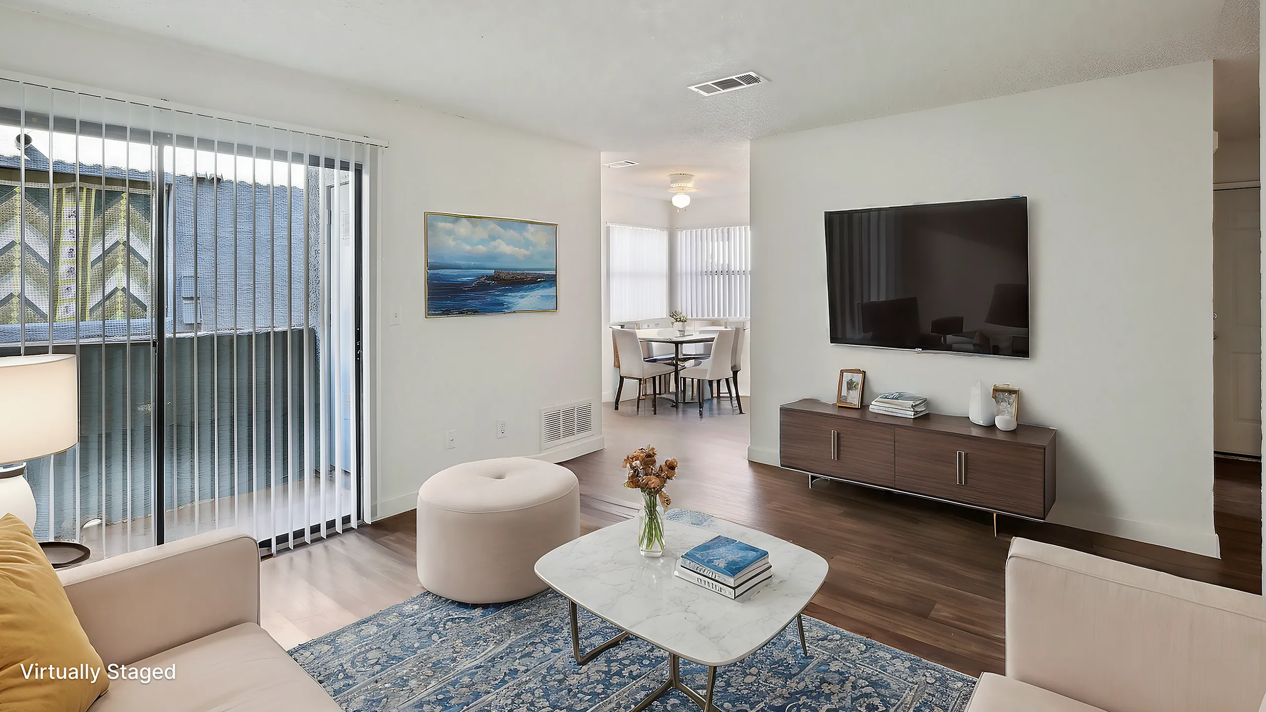 Chic and modern living room with a cozy seating area, large flat-screen TV, and elegant decor, leading to a bright dining space with stylish furniture and abundant natural light.