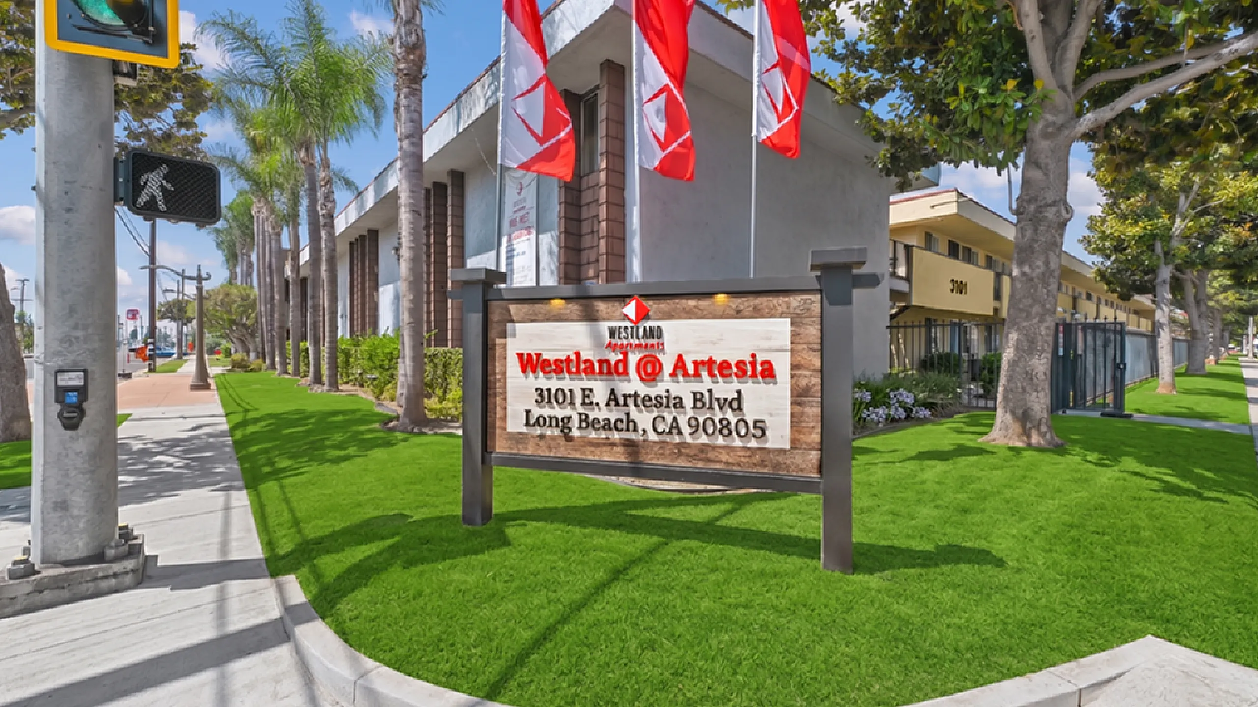 Inviting exterior view of Westland @ Artesia in Long Beach, showcasing vibrant landscaping and a welcoming entrance sign.