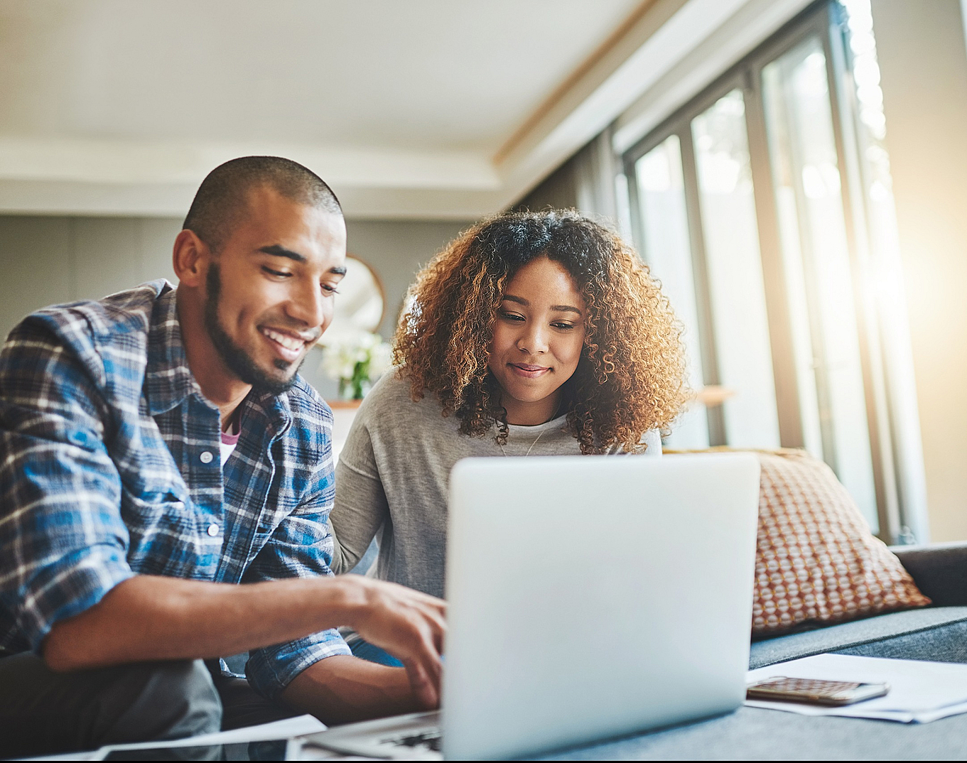 Bright and modern living space with two people collaborating on a laptop, exuding warmth and productivity in a stylish apartment setting.