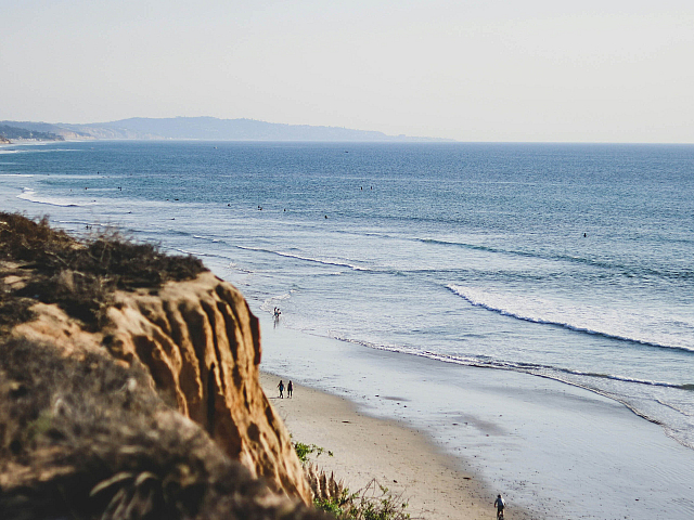 view of the beach with people walking from a hill
