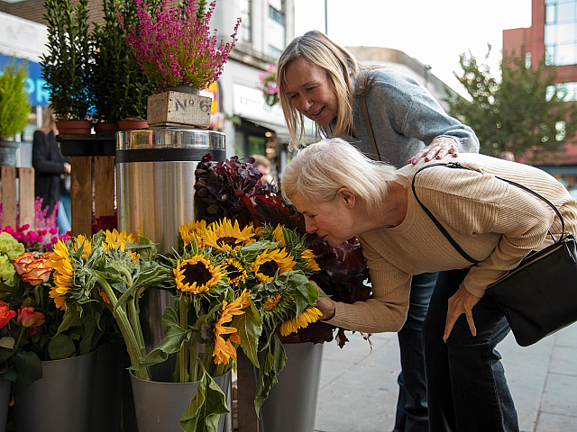 side view of woman smelling flowers at the farmers market