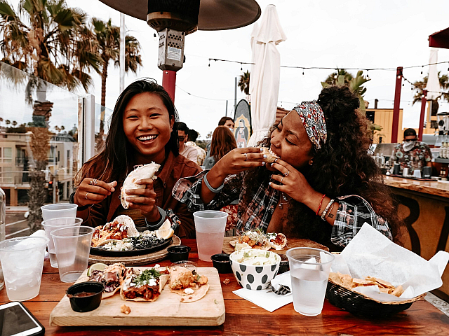 two women eating tacos in a patio restaurant