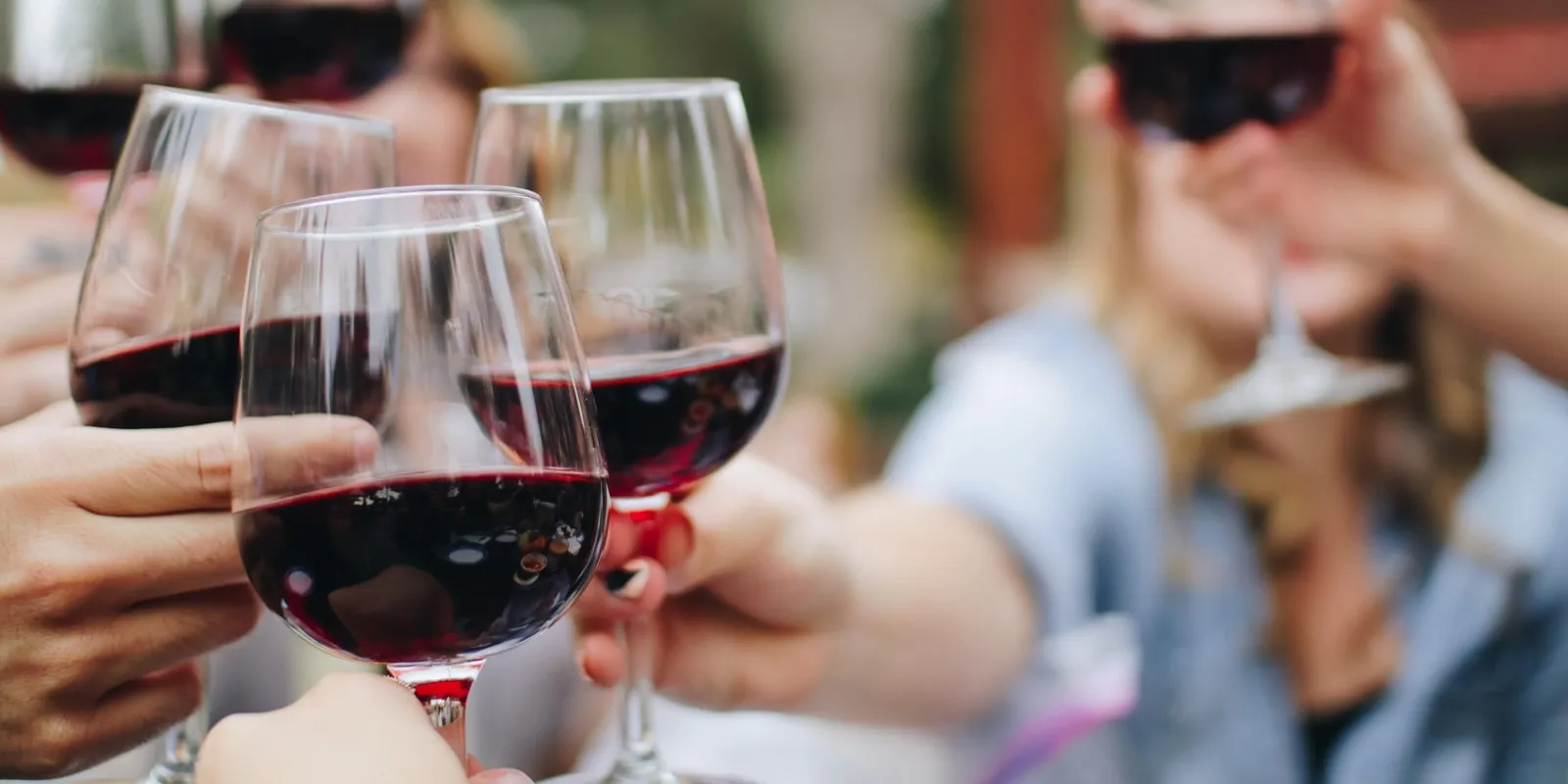 People doing a cheers with red wine glasses
