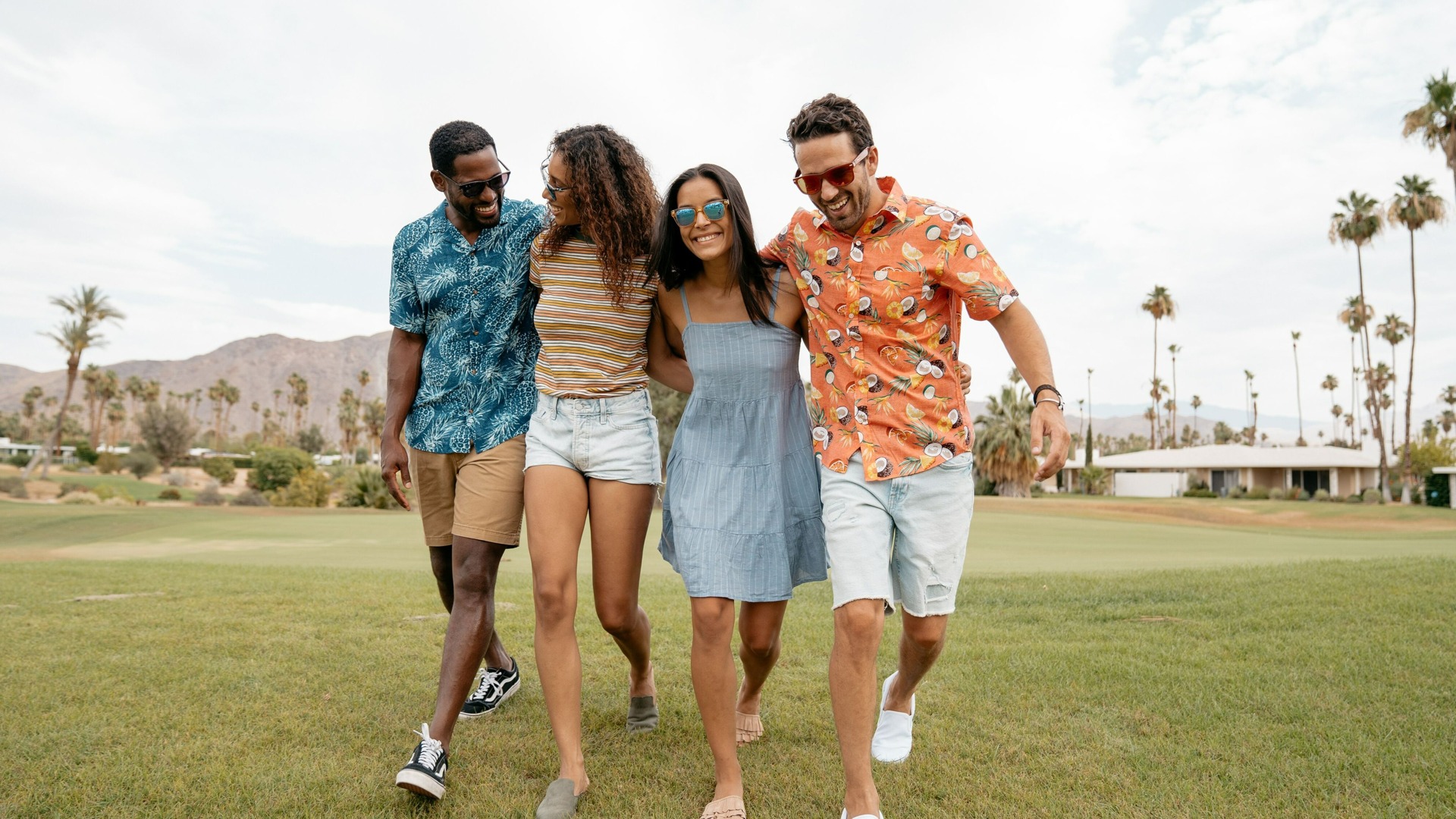 Group of diverse freindsl walking with palm trees in the background