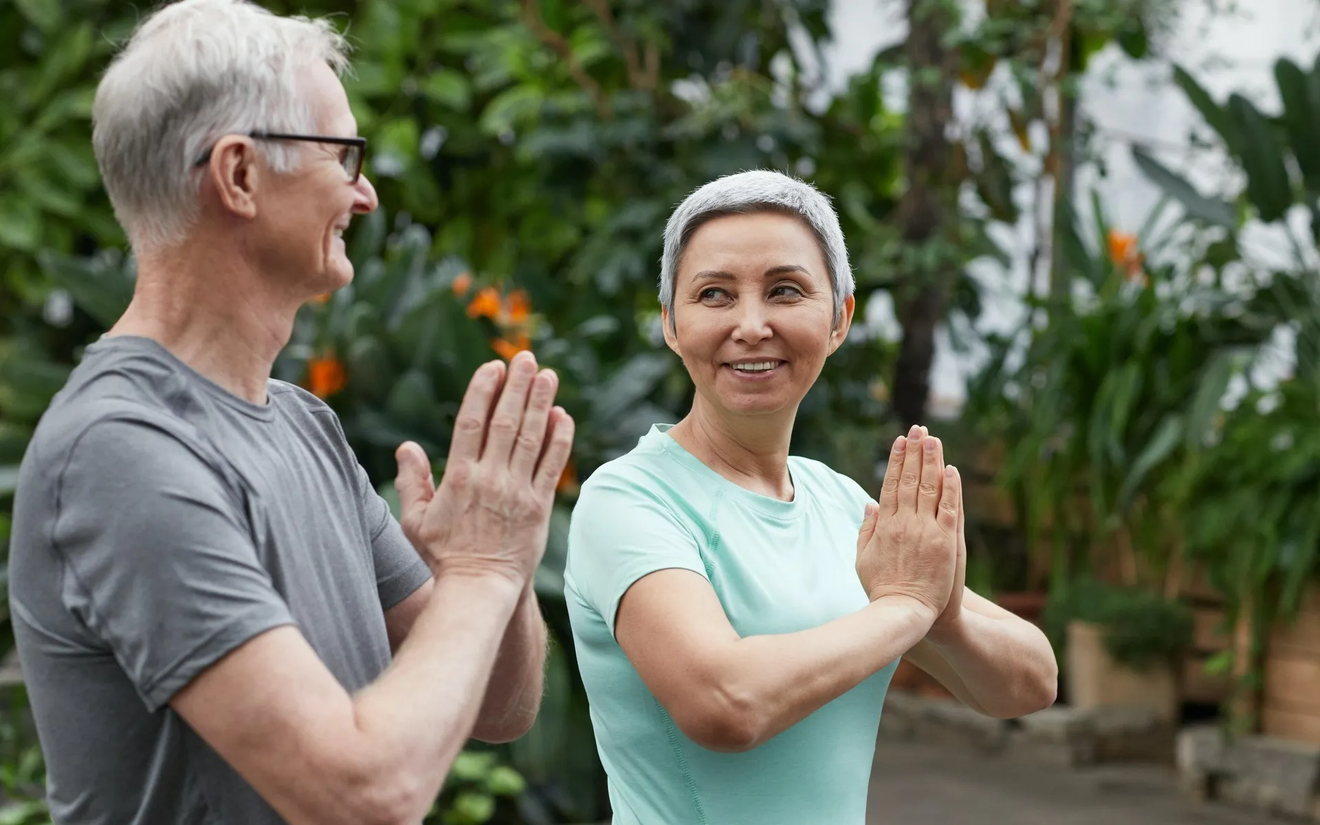 Two seniors doing Yoga with lush landscaping
