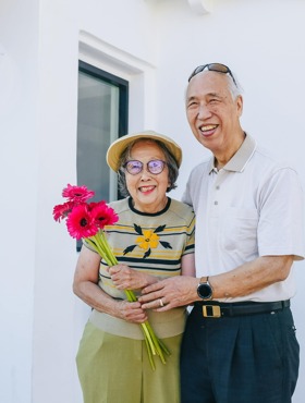 two seniors - one man and a woman holding flowers