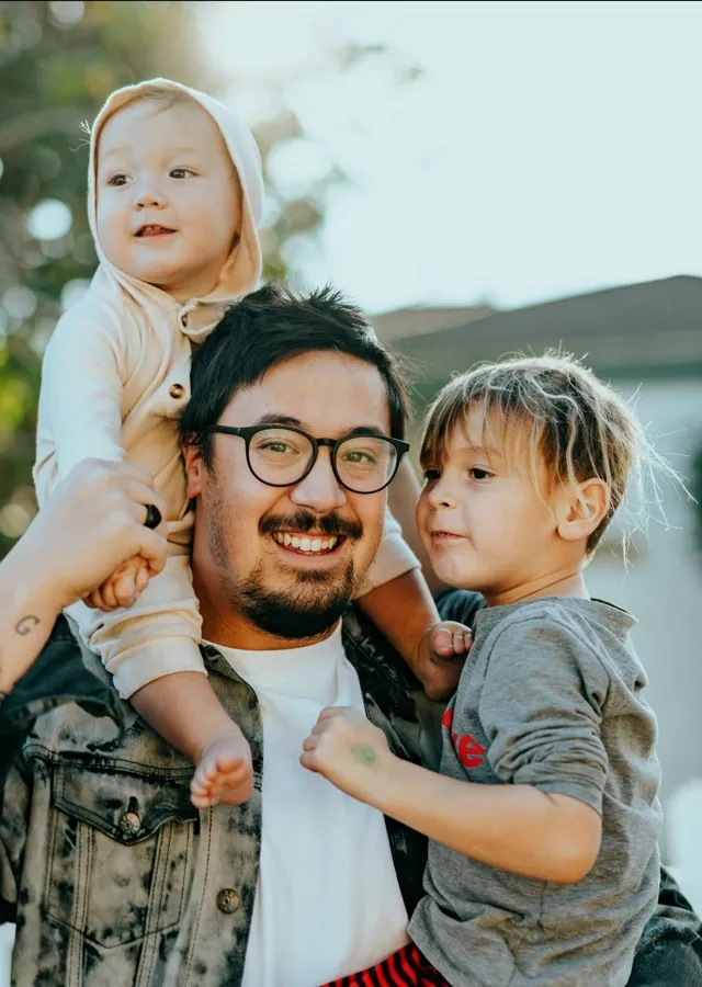 man carrying two small kids