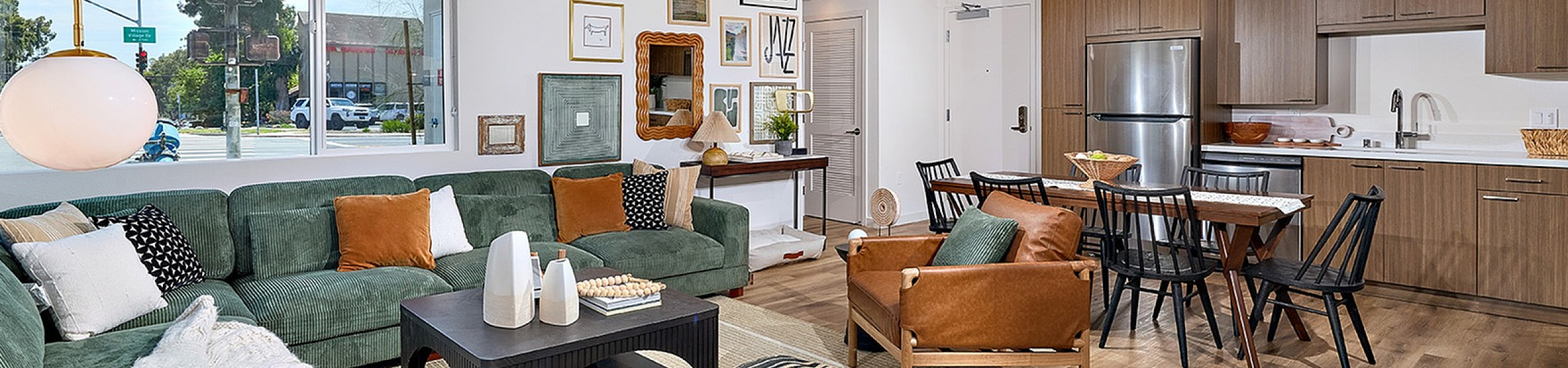 staged living room with faux wood like flooring and kitchen with stainless steel appliances at DEZI