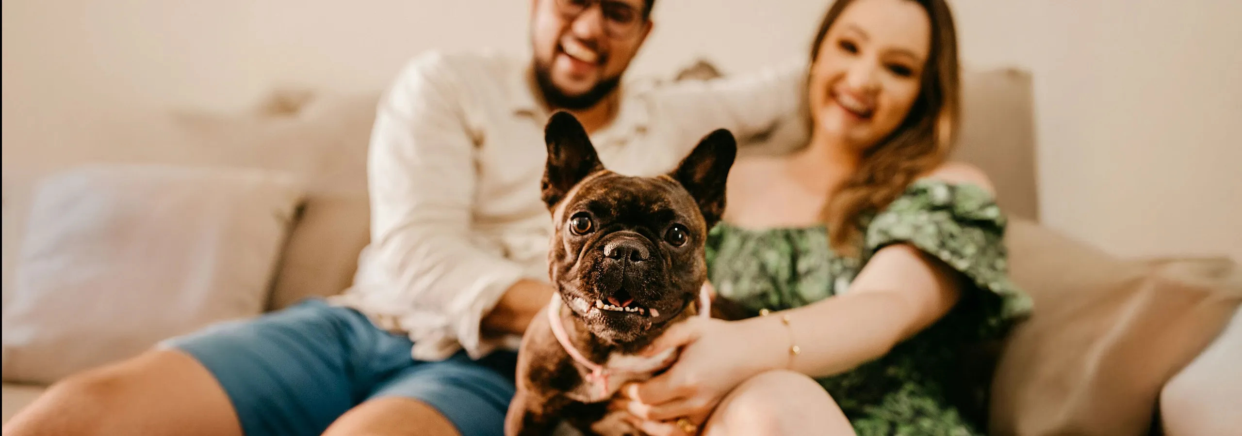 two-people-sitting-on-a-sofa-with-their-small-dog-in-the-middle