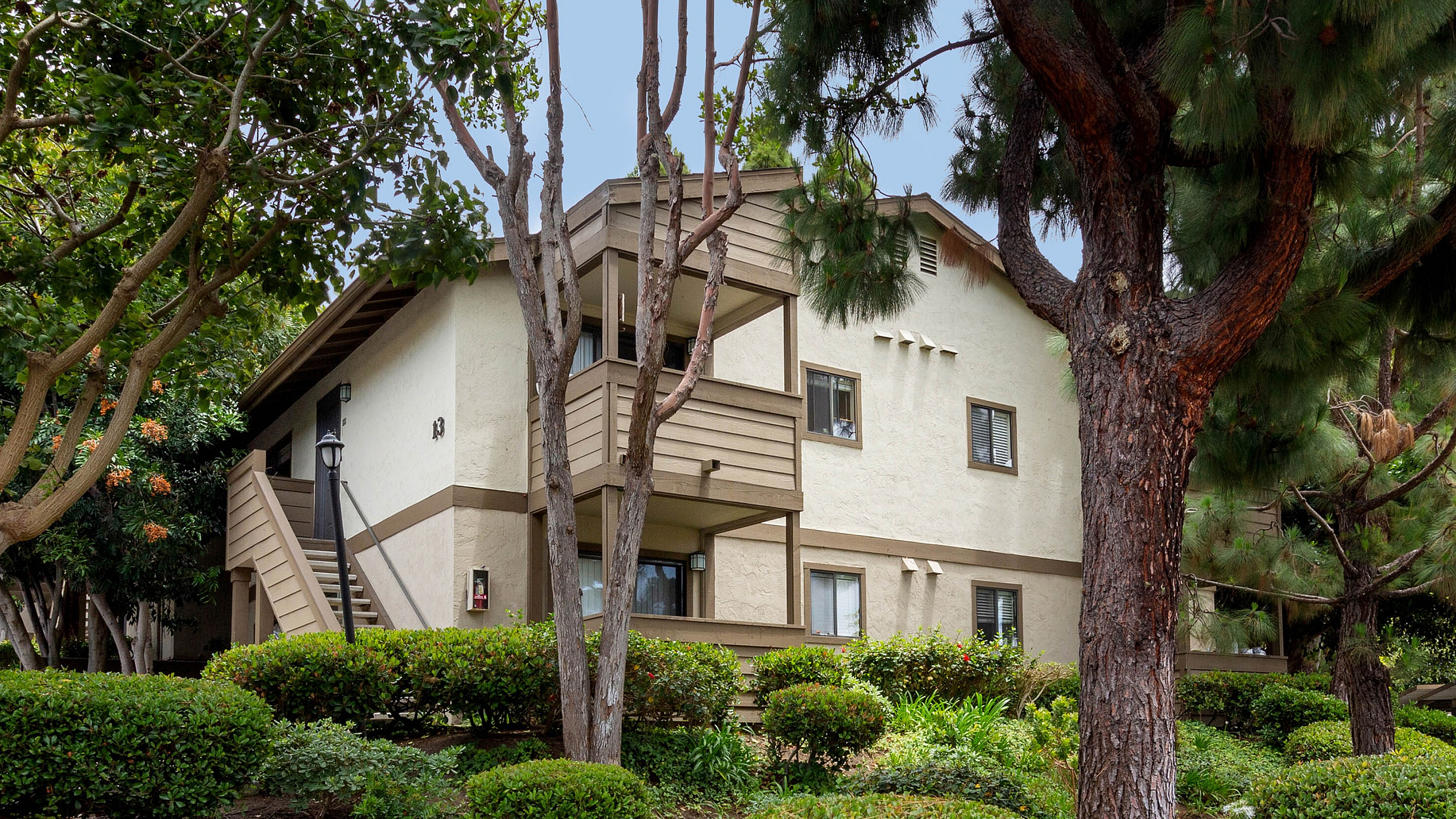 Multi-story apartment buildings tucked into lush, mature green landscaping.