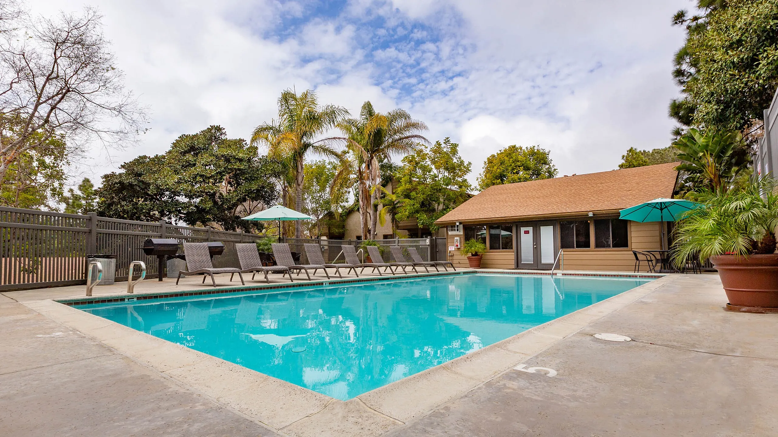 Sparkling swimming pool surrounded by lounge chairs and tropical palm trees.